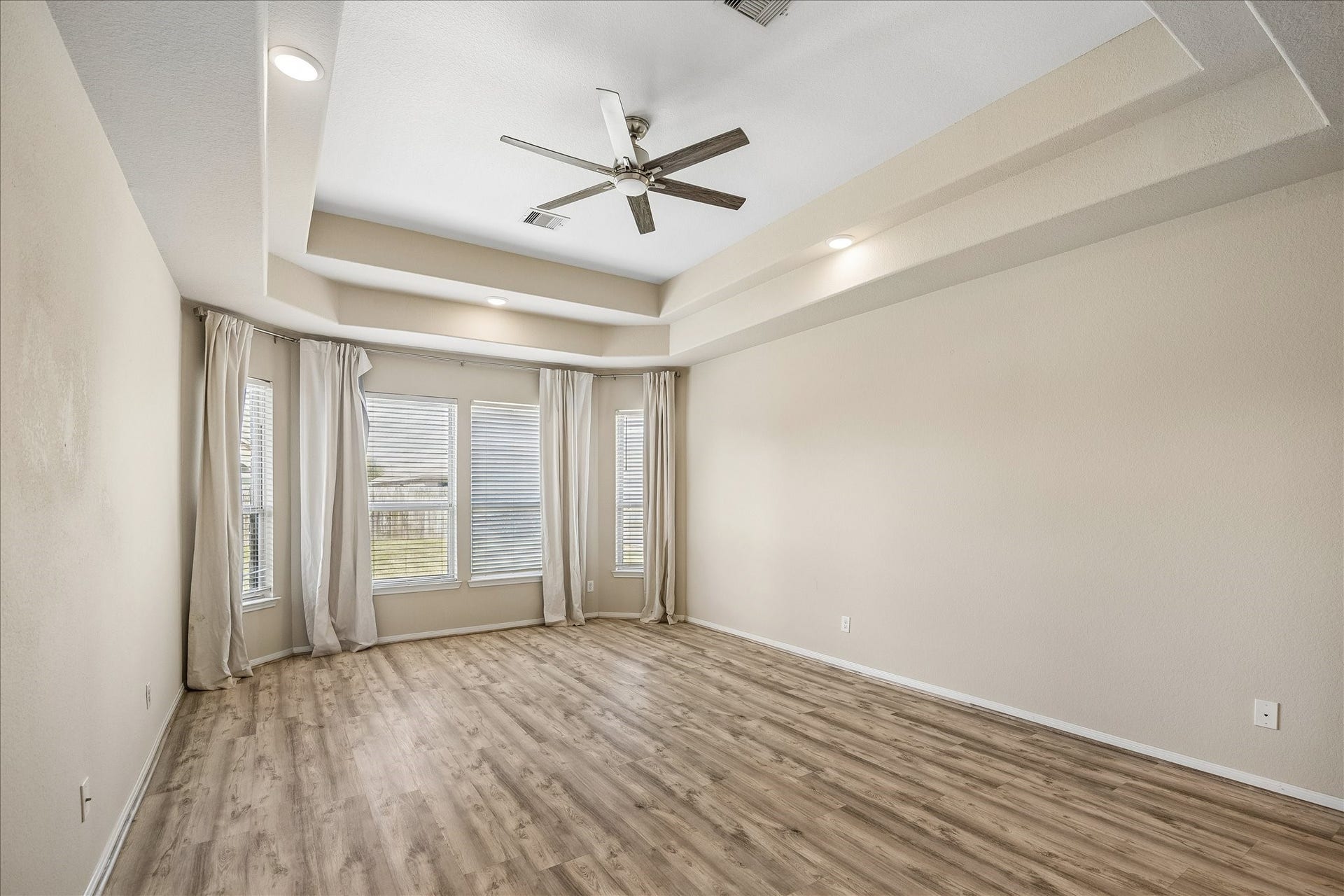 10018 Mahaffey Road, Tomball, TX 77375 Large primary bedroom with large windows, tray ceiling and wood floors.