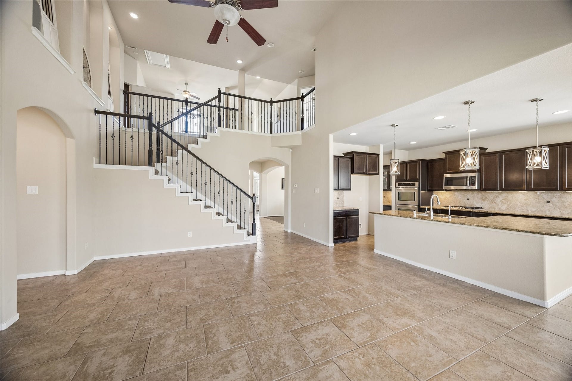 10018 Mahaffey Road, Tomball, TX 77375 The spacious living room features high ceilings, a striking staircase with wrought-iron balusters, and beautiful tile flooring.