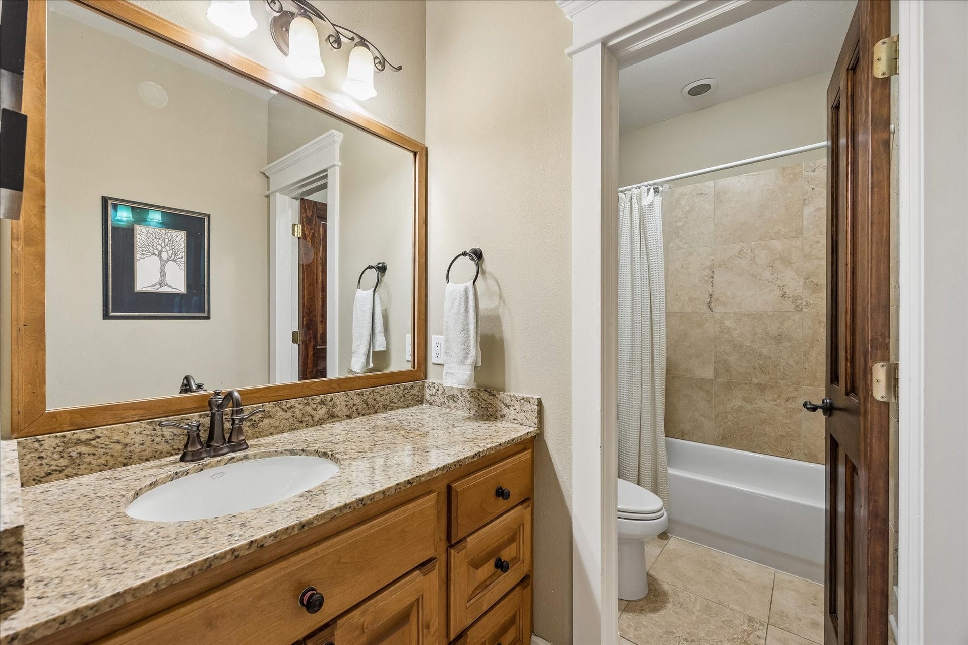 The upstairs guest bath keeps things polished and practical with granite counters, warm wood cabinetry and a separate water closet with the toilet and tub/shower combination tucked away for added privacy.