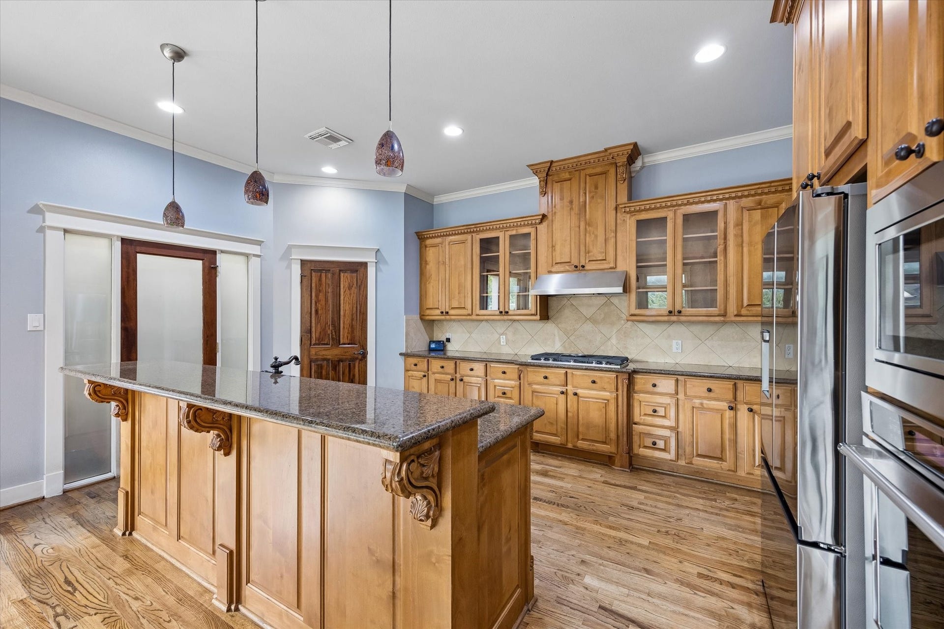 This kitchen makes cooking for a crowd feel like part of the fun. A huge island with bar seating anchors the space, while rich wood cabinetry, granite counters and Jenn Air stainless steel appliances, including a 5 burner gas range and beverage chiller, pair with double pantries to keep everything organized, stocked and ready for your next gathering.