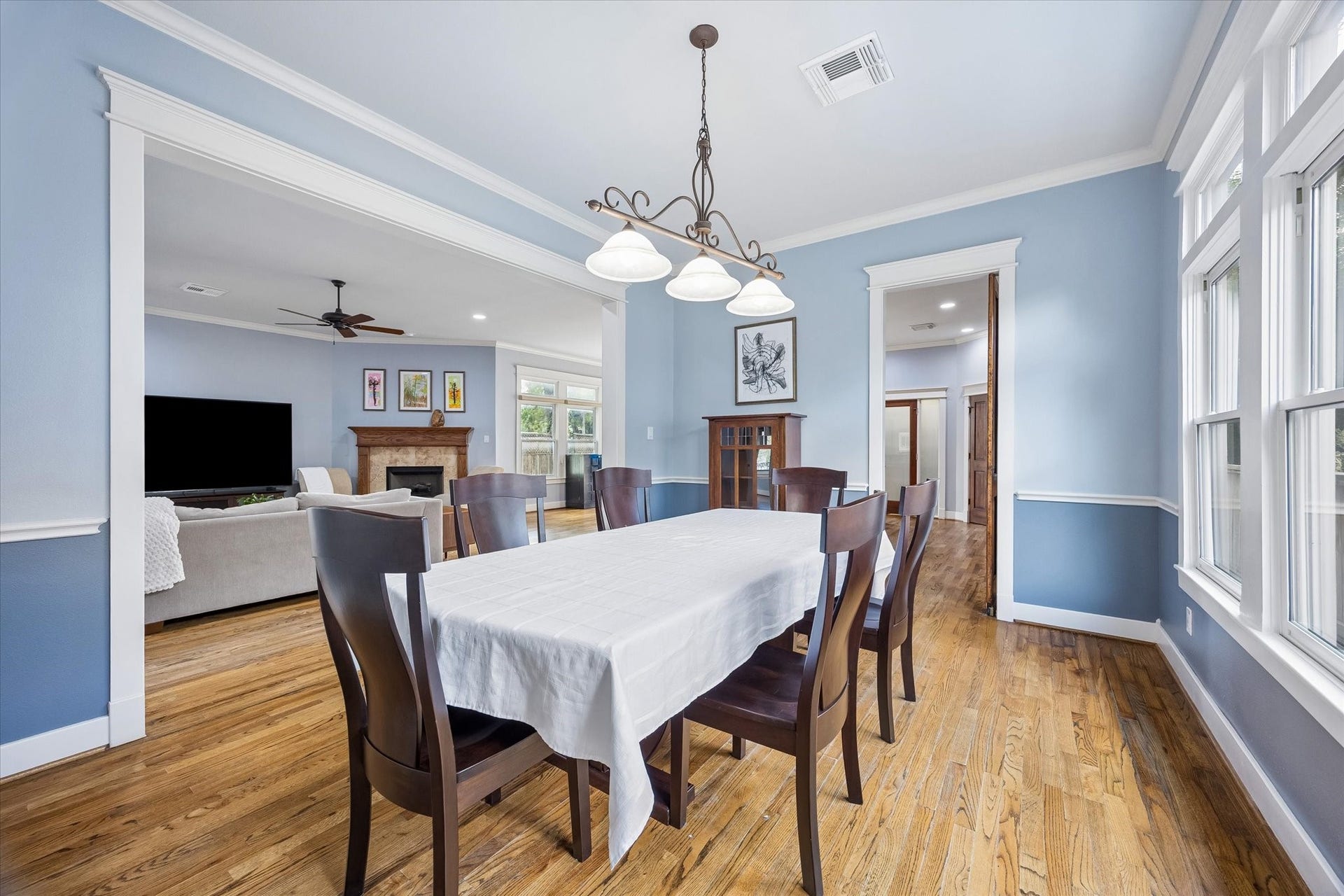 This elegant dining room connects beautifully with the main living area and kitchen, making entertaining feel easy and natural. Hardwood floors, designer paint, a stylish chandelier, crisp millwork and abundant natural light give the space a polished feel without making it feel too formal.