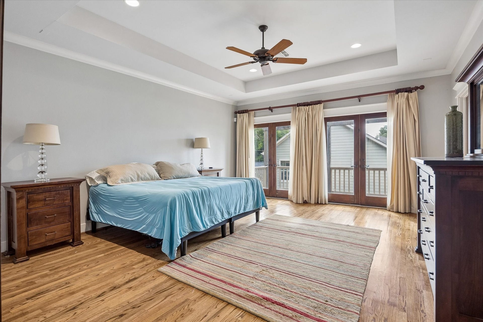Upstairs, the primary retreat feels like your own little escape. Warm wood floors, a tray ceiling and two sets of French doors opening to the backyard balcony create a space that feels comfortable, relaxed and easy to settle into.