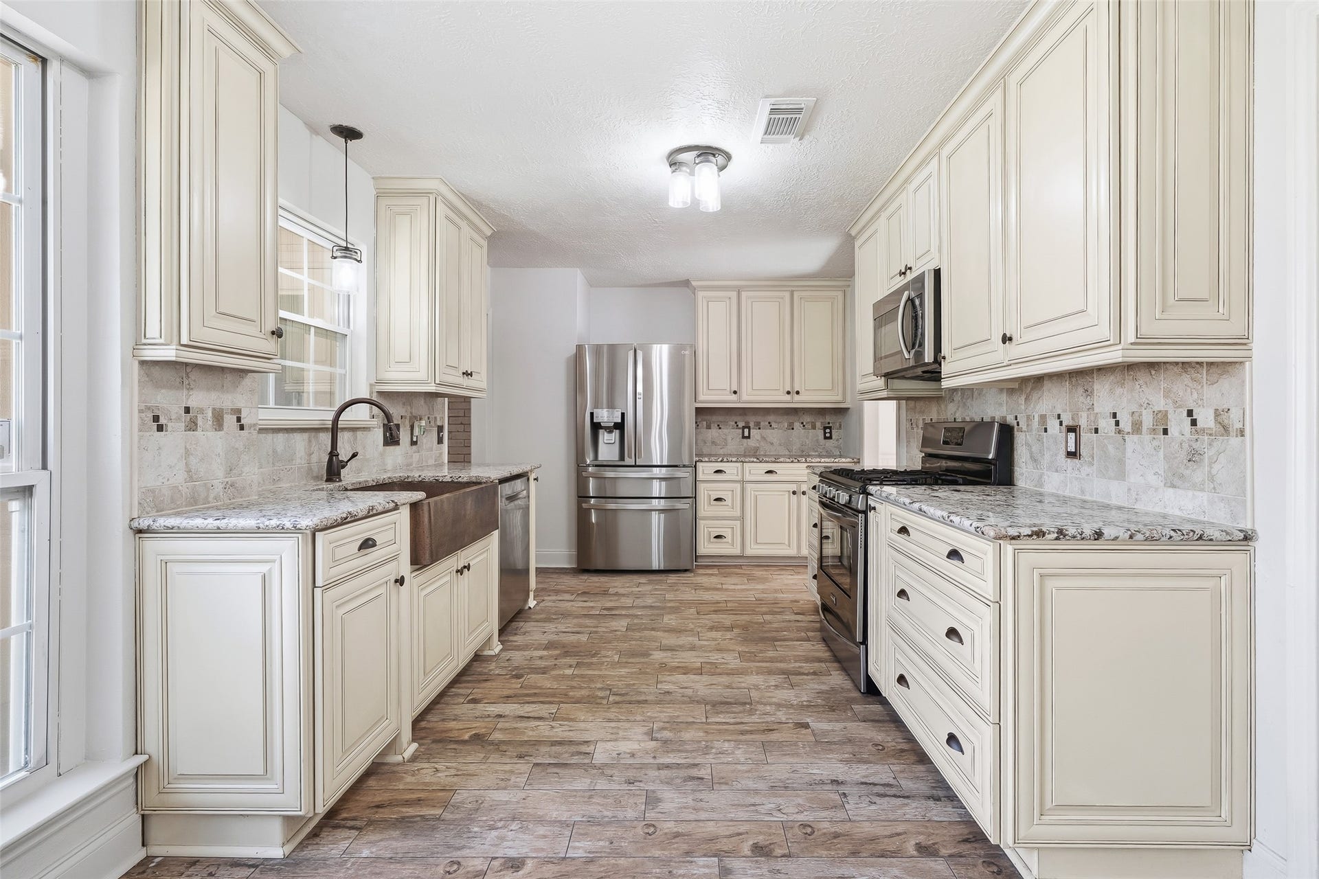 25806 Old Carriage Lane, Spring, TX 77373 Elegant kitchen featuring cream cabinetry, granite countertops, and stainless steel appliances, accented by a farmhouse sink and tile backsplash.