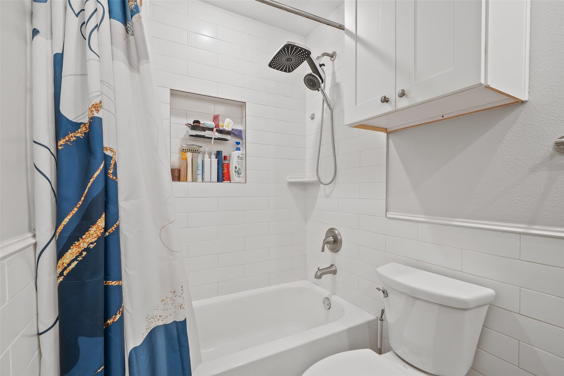25806 Old Carriage Lane, Spring, TX 77373 Modern bathroom featuring a sleek white subway tile design, a luxurious showerhead, and convenient built-in cabinet for storage.