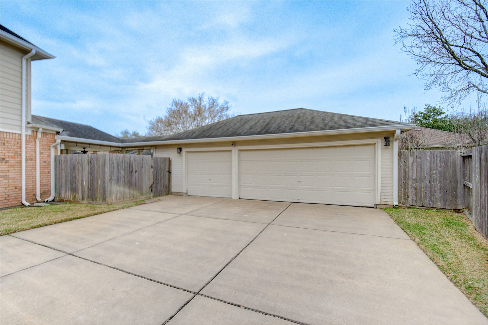 A spacious driveway leading to a 3-car garage, surrounded by wooden fencing.