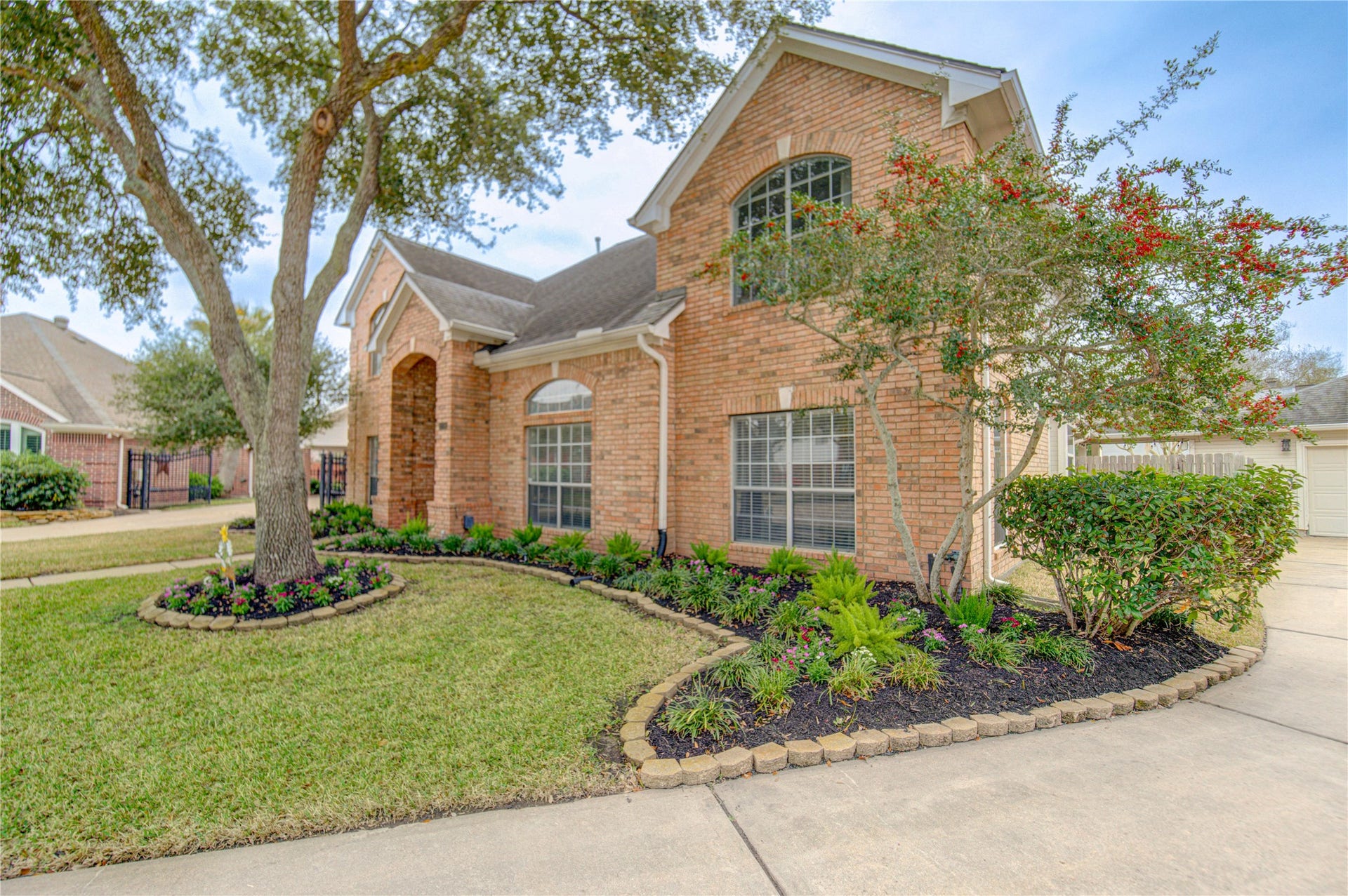 Another view of the front yard featuring a newly planted flower bed with beautiful blooms.