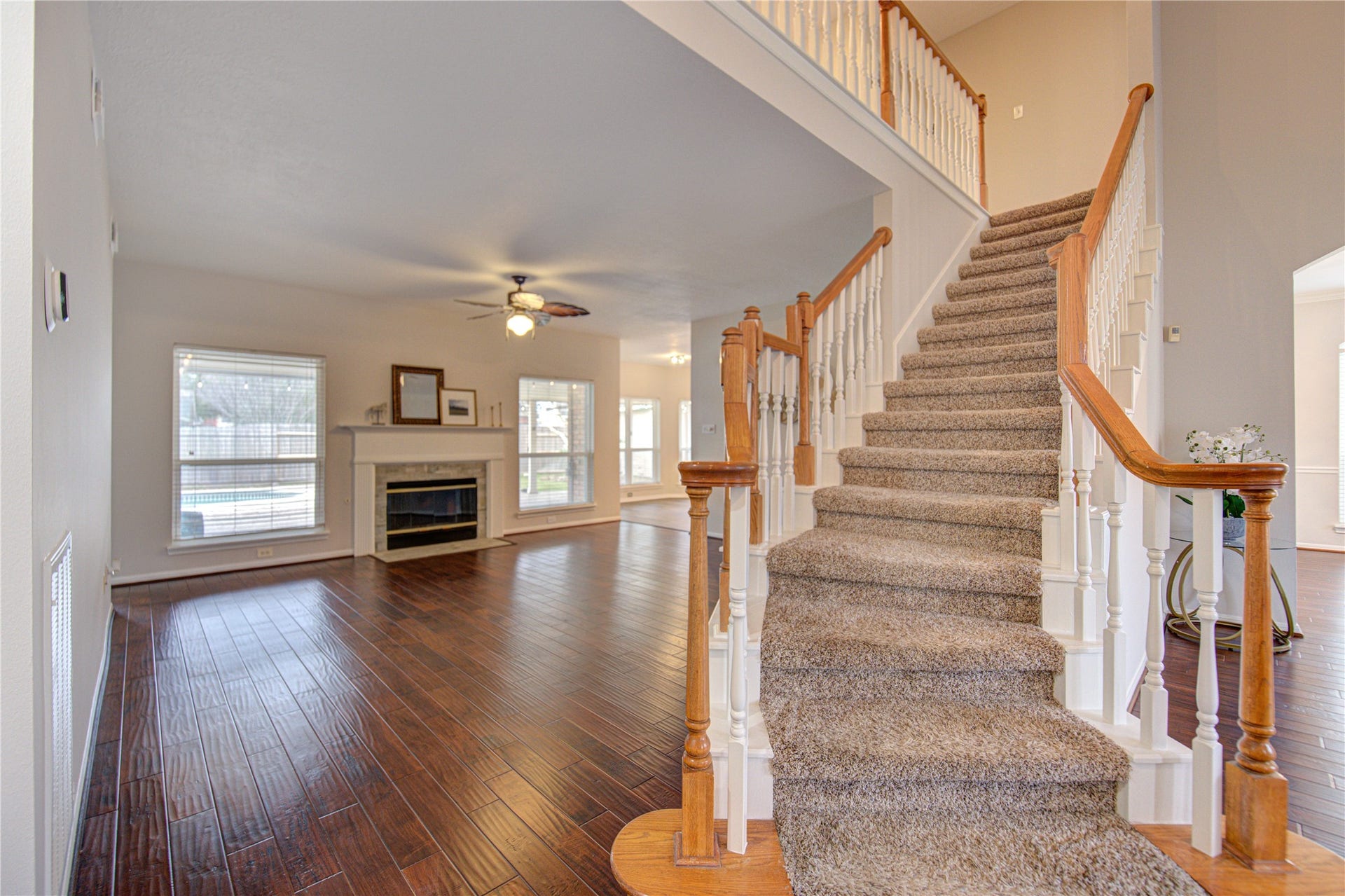 A beautiful, curved staircase adds charm and sophistication, and the room is well-lit with natural light from large windows.