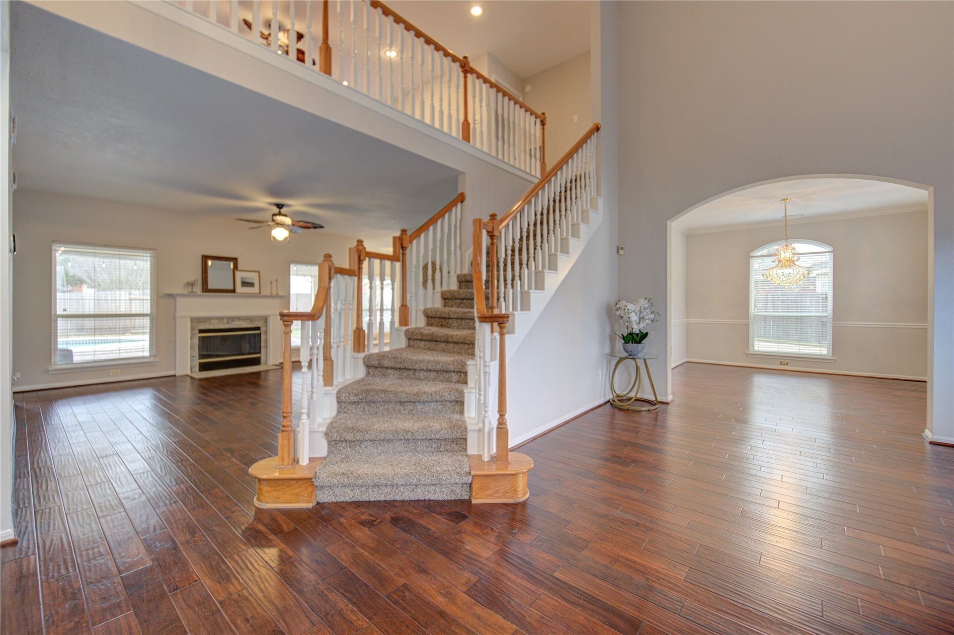 This spacious room features elegant hardwood floors, high ceilings, and large arched windows that provide ample natural light. The open design flows into an adjacent dining area with a chic chandelier, creating a welcoming and sophisticated atmosphere.