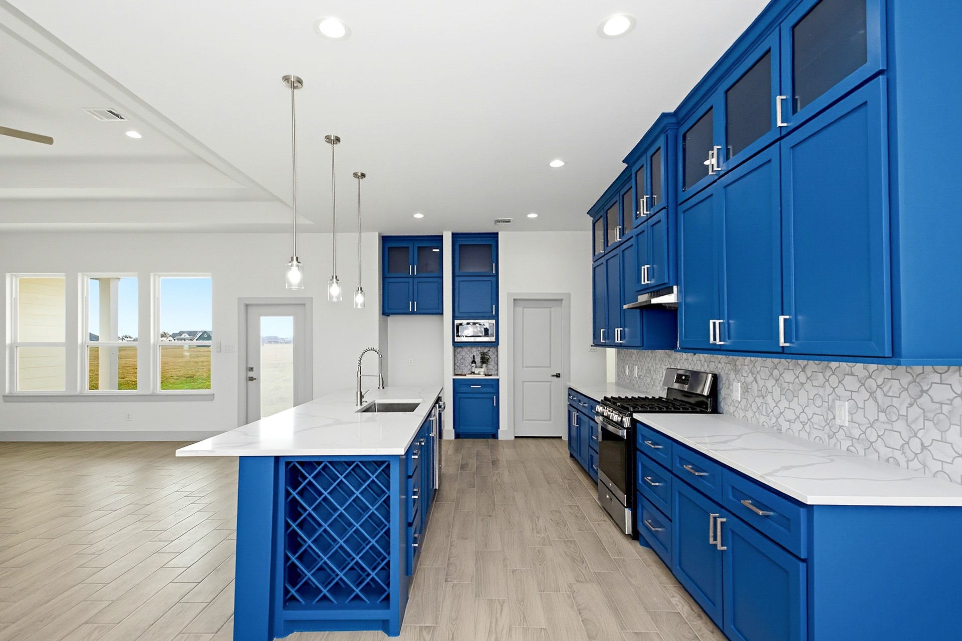 619 Longhorn Trail, Angleton, TX 77515 Stunning 19x14 kitchen with vibrant blue cabinetry, sleek quartz countertops, and modern stainless-steel appliances, all complemented by an open layout and ample natural light.
