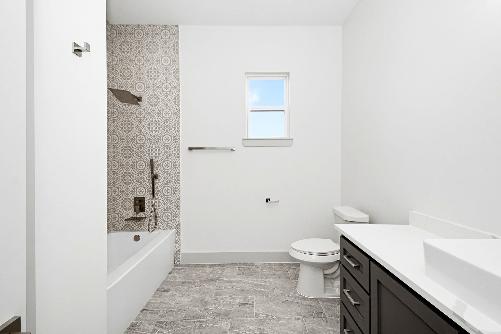 619 Longhorn Trail, Angleton, TX 77515 Elegant 10x10 secondary bathroom featuring a sleek vanity, patterned tile accents, and a bathtub with modern fixtures.