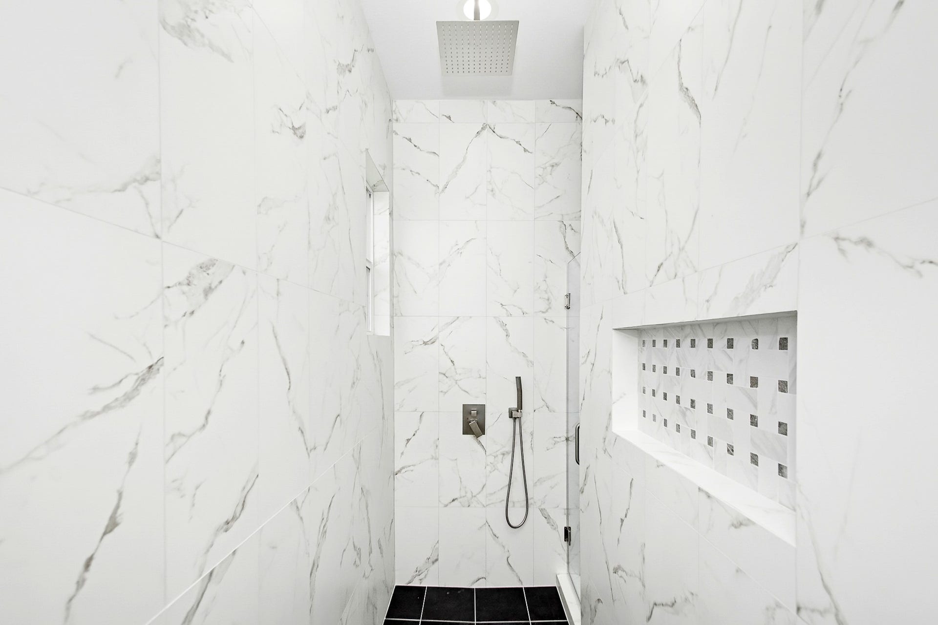 619 Longhorn Trail, Angleton, TX 77515 Luxurious shower with elegant marble walls, a sleek rainfall showerhead, and a modern recessed shelf for convenience.