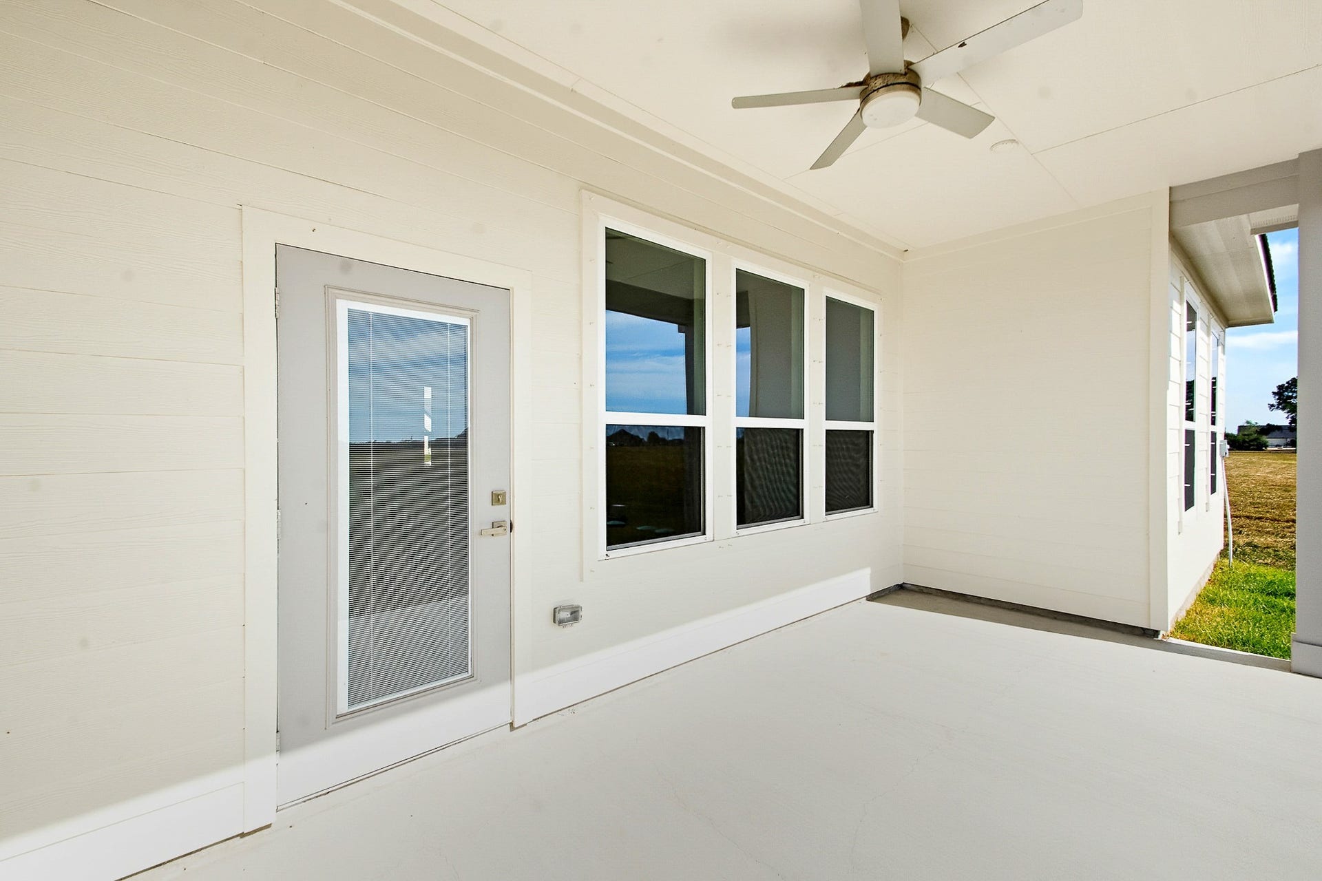 619 Longhorn Trail, Angleton, TX 77515 Spacious covered patio with modern ceiling fan and large windows, offering a seamless indoor-outdoor living experience with serene views. Situated on a 1 Acre lot.