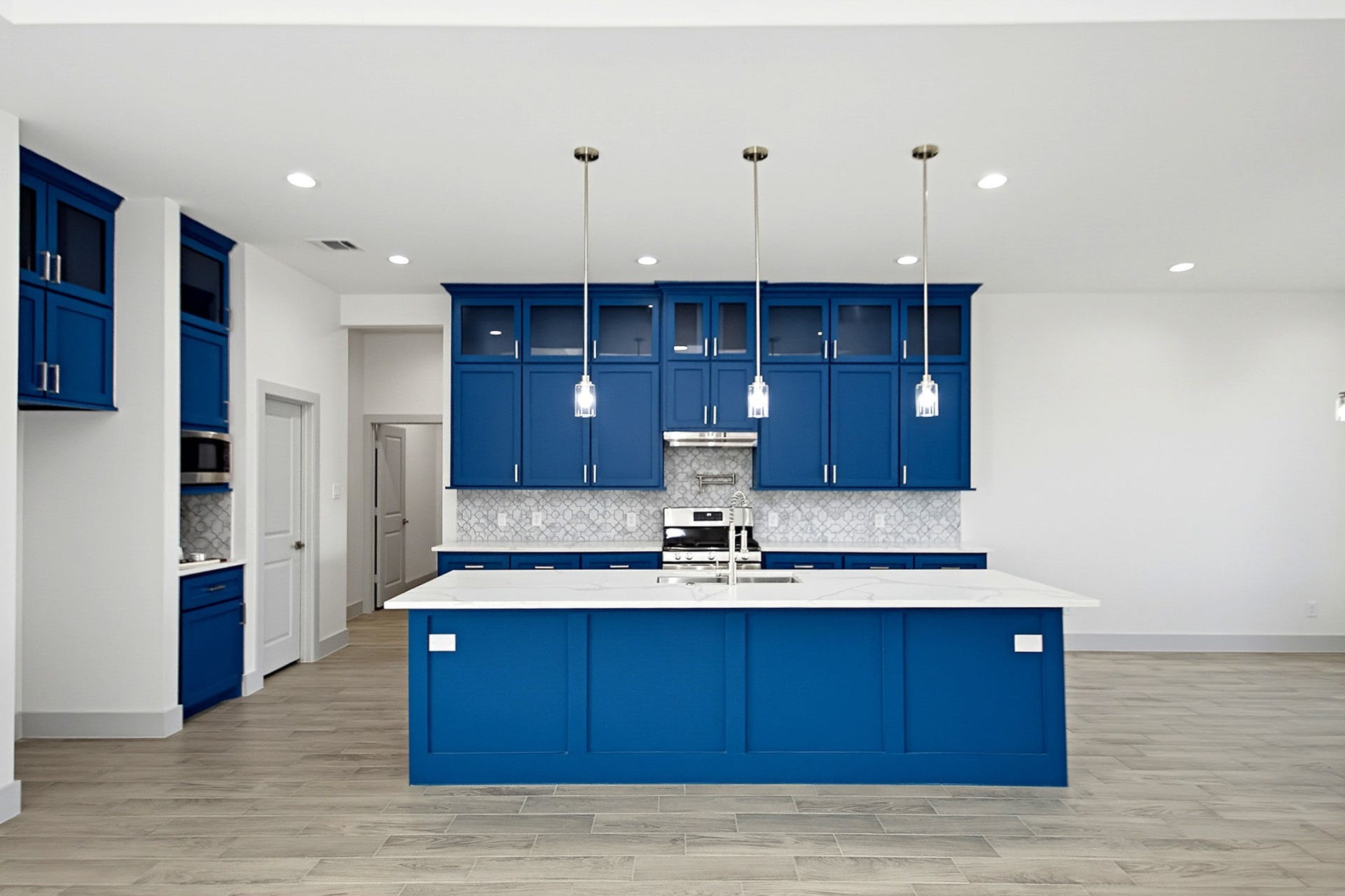 619 Longhorn Trail, Angleton, TX 77515 Stunning modern kitchen with vibrant blue cabinetry, sleek quartz countertops, and stylish pendant lighting, creating a perfect blend of elegance and functionality.
