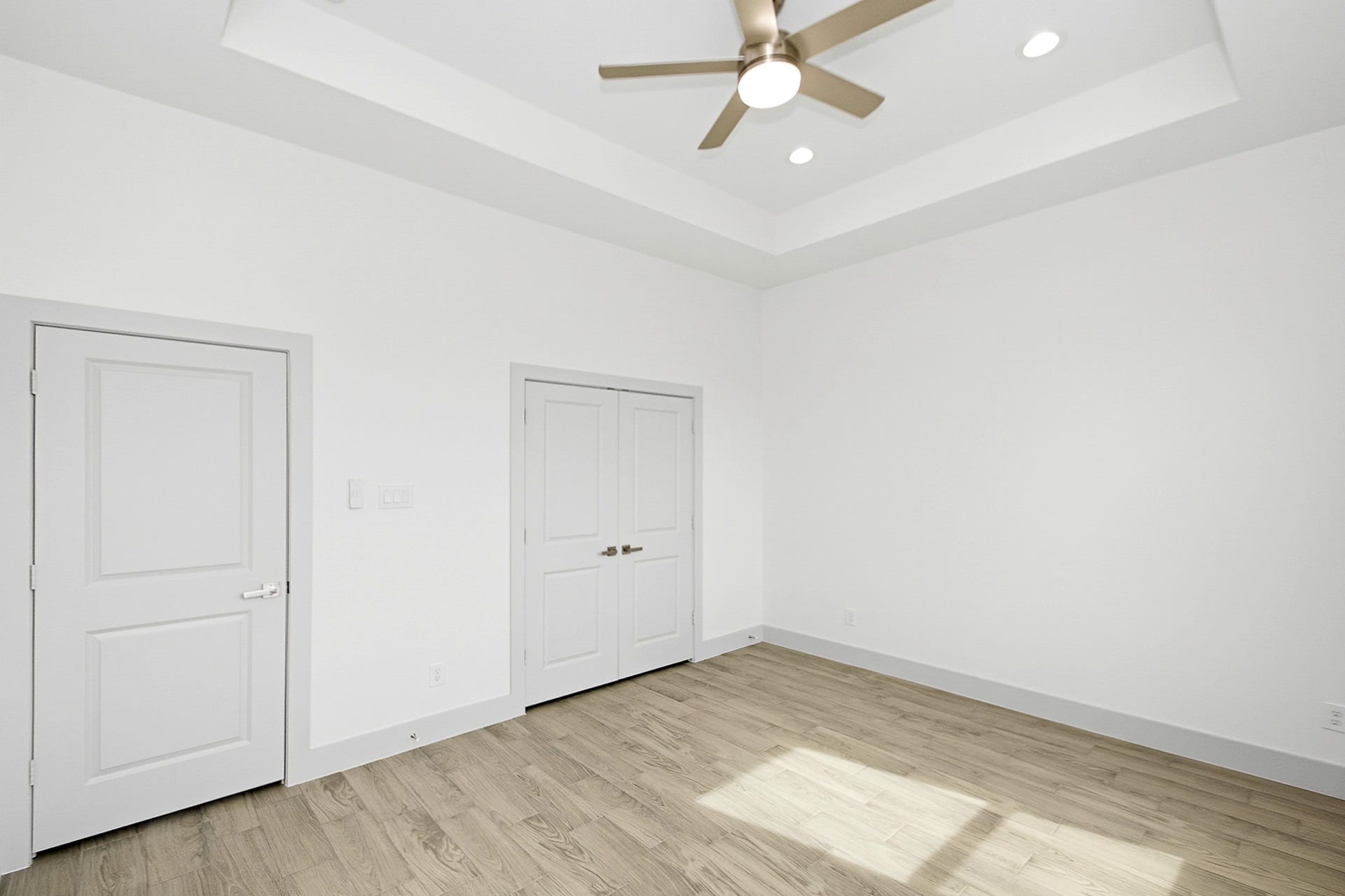 619 Longhorn Trail, Angleton, TX 77515 Bright and airy 14.5x12 third bedroom featuring sleek tile flooring, tray ceilings a modern ceiling fan, recessed lighting, double doors are the closet, offering a clean and contemporary space.