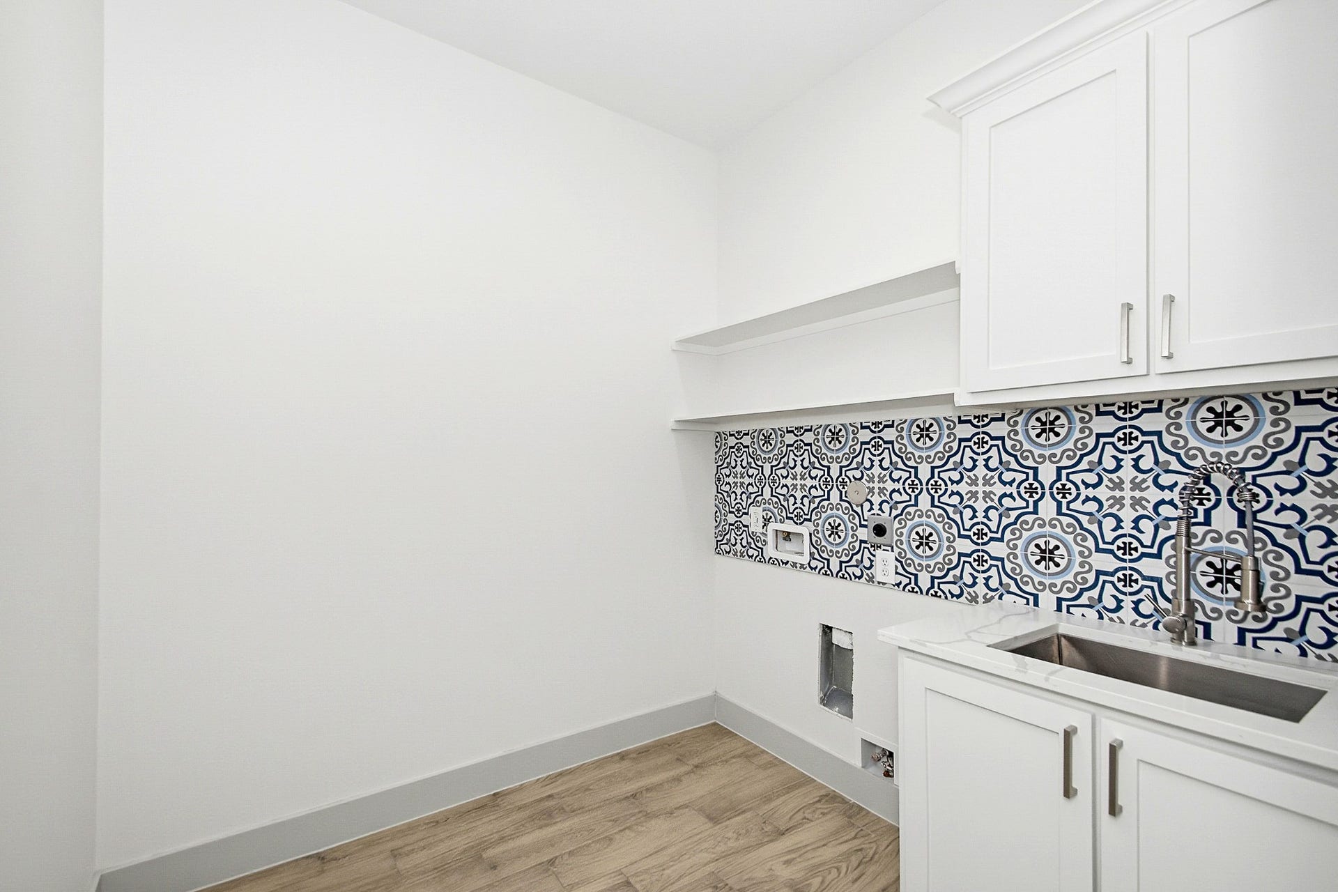 619 Longhorn Trail, Angleton, TX 77515 Sleek laundry 8x 8 laundry room featuring elegant white cabinetry, a modern sink, and vibrant patterned tiles, complemented by warm tile flooring.