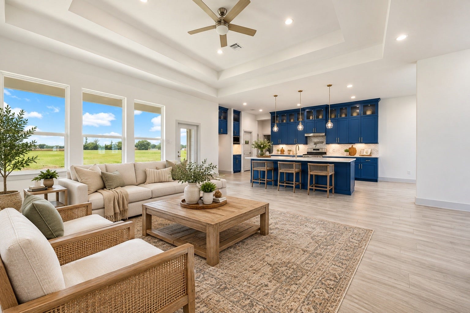 619 Longhorn Trail, Angleton, TX 77515 Spacious staged 19x16 open-concept living area with elegant tray ceiling, abundant natural light, and a modern kitchen featuring striking blue cabinetry and a large island.