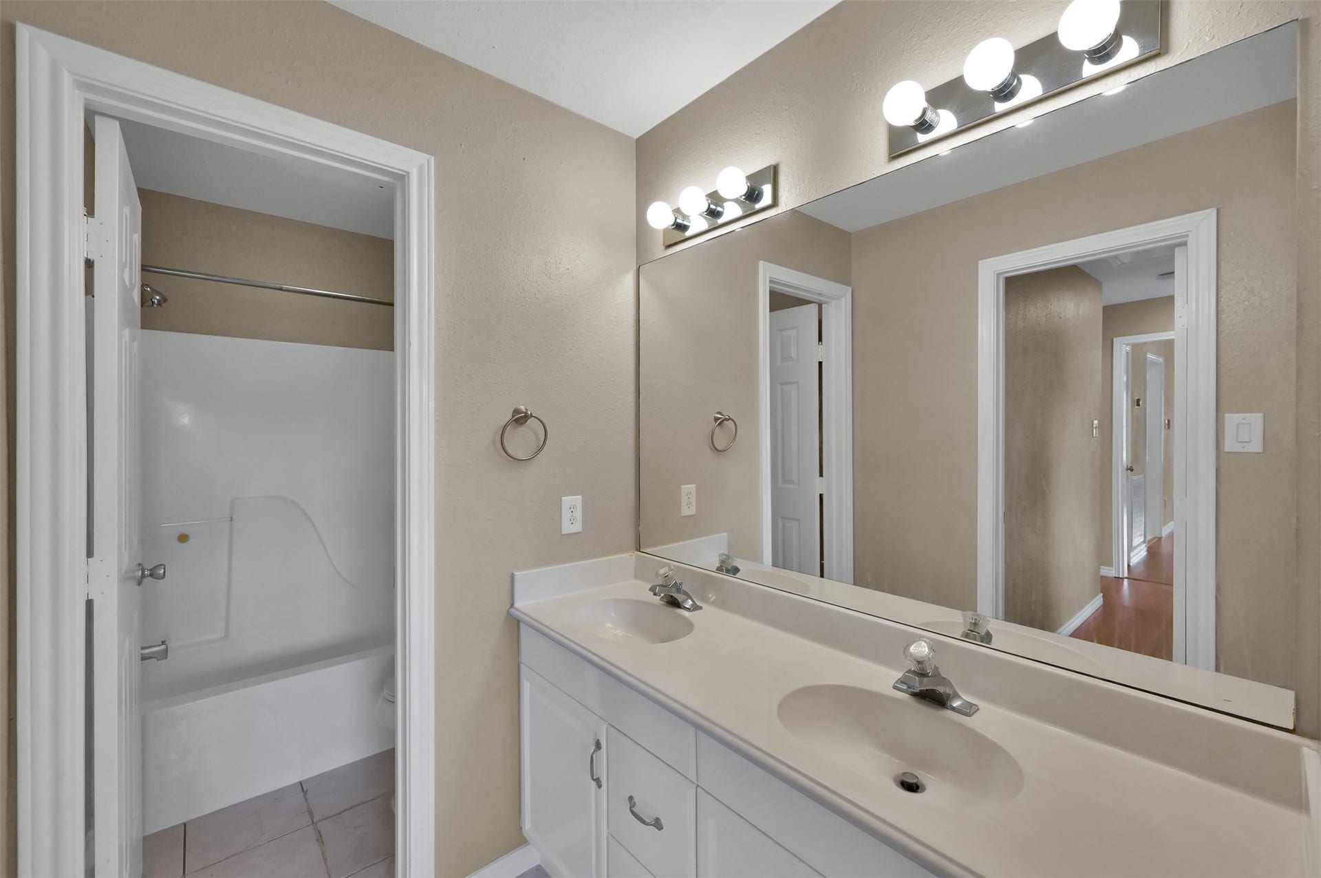 1141 Lovett Street, Tomball, TX 77375 Bathroom featuring a double vanity with ample counter space, bright lighting, and an adjacent shower-tub combo, perfect for a relaxing retreat.