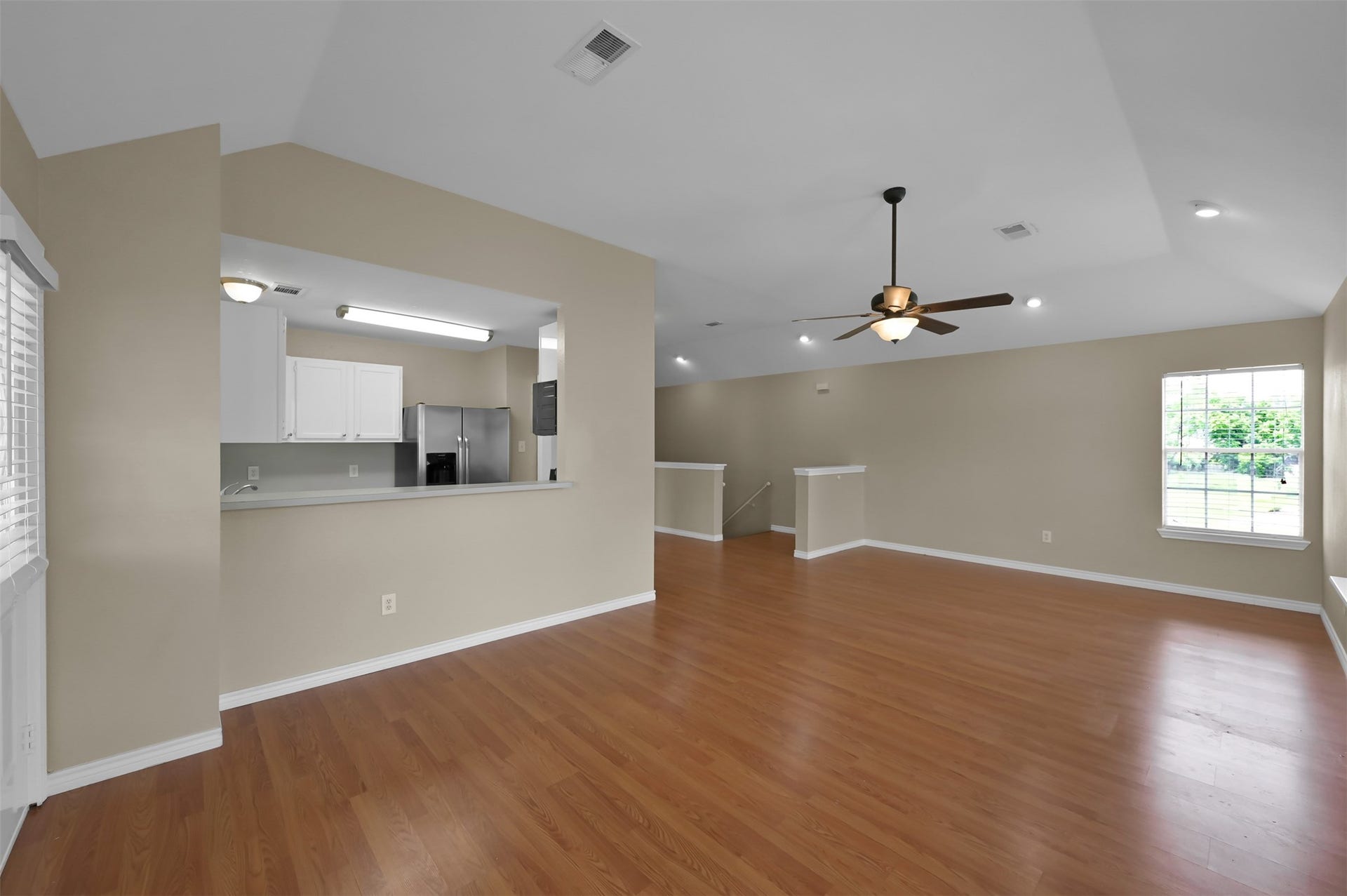 1141 Lovett Street, Tomball, TX 77375 Spacious open-concept living area with warm wood flooring, high ceilings, and ample natural light, featuring a modern kitchen with stainless steel appliances.
