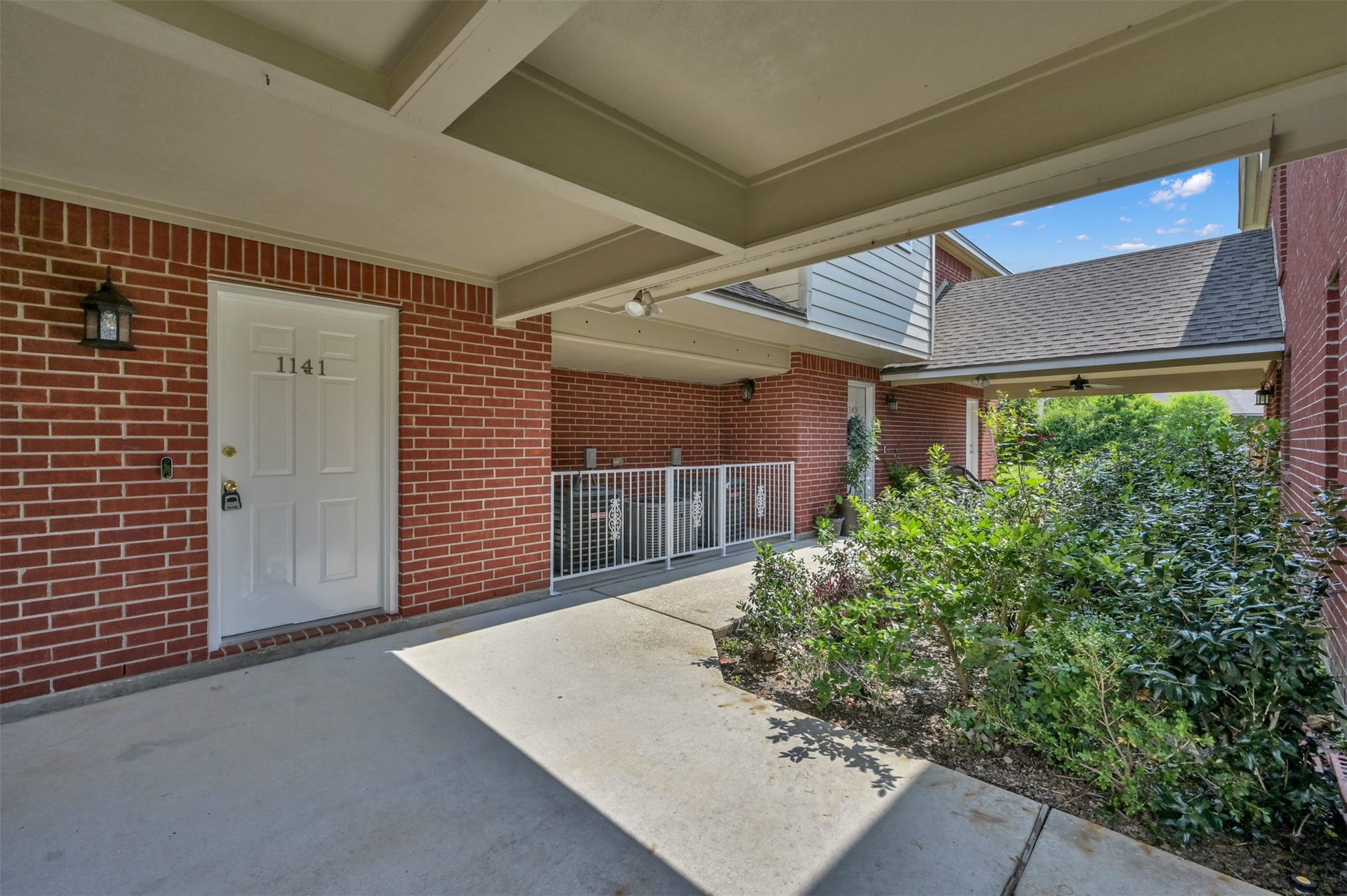 1141 Lovett Street, Tomball, TX 77375 Charming brick exterior with a welcoming Breezeway area, complemented by lush greenery and a secure entrance.