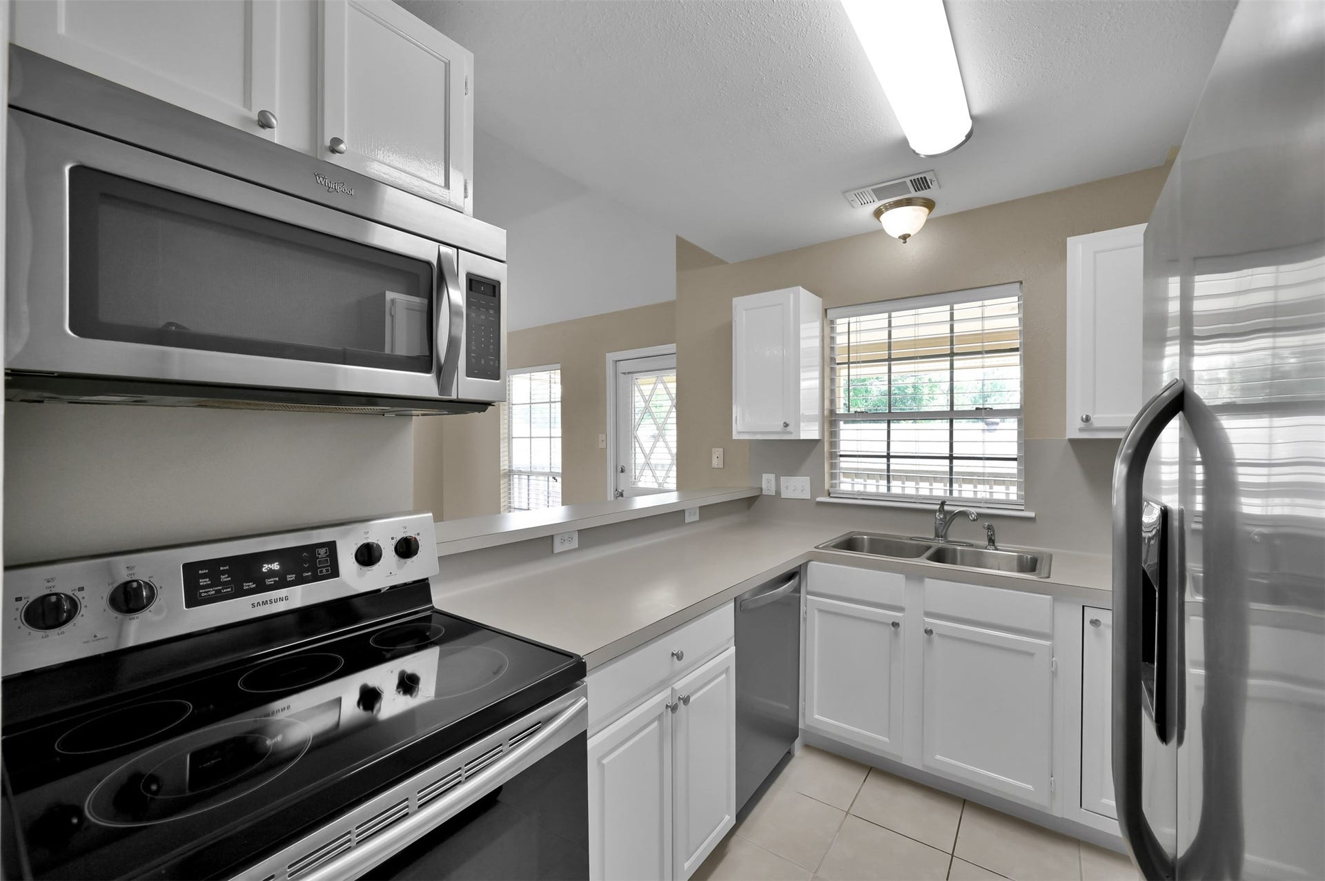 1141 Lovett Street, Tomball, TX 77375 Modern kitchen with sleek stainless steel appliances, bright white cabinetry, and ample natural light through large windows.