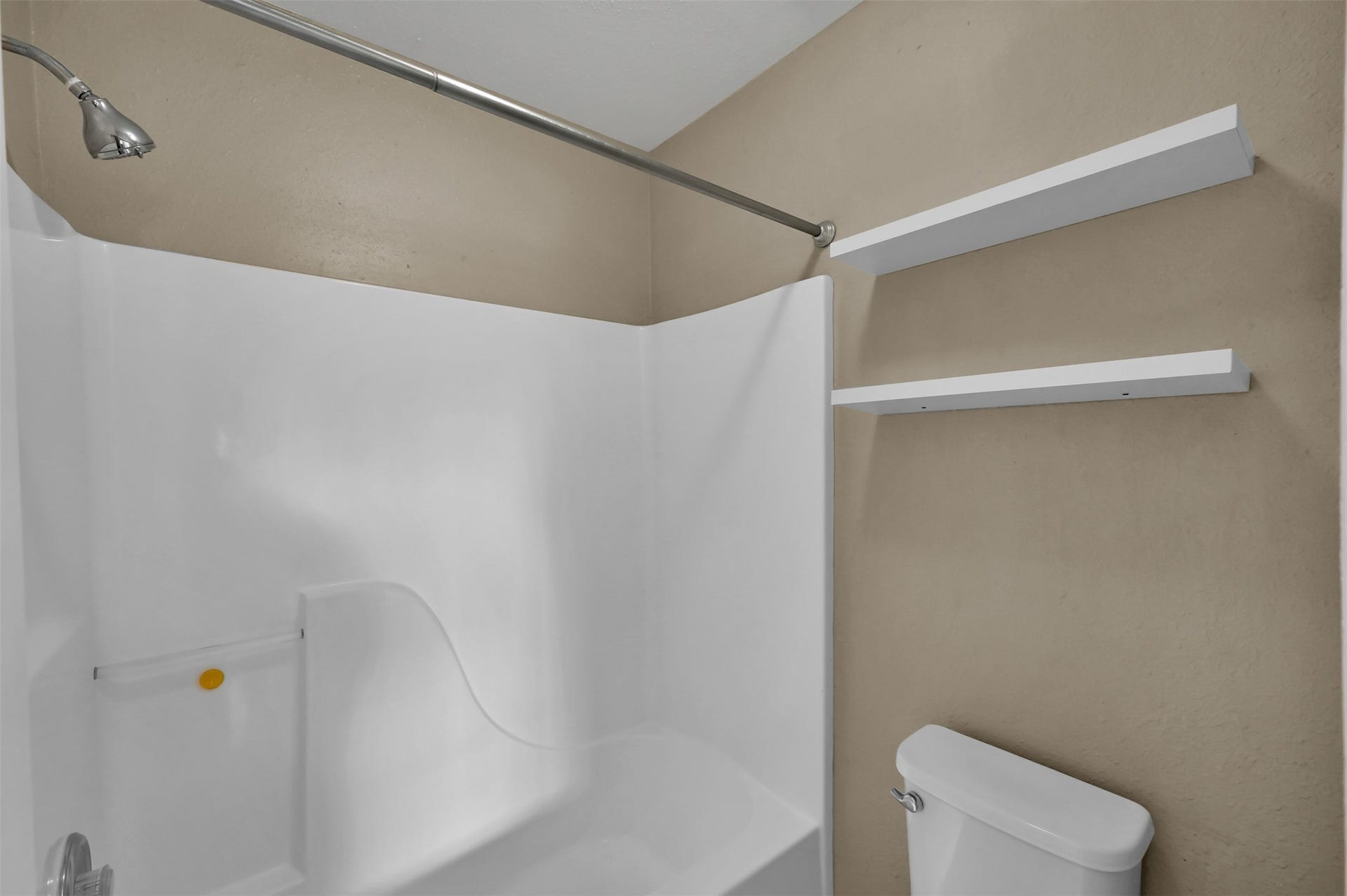 1141 Lovett Street, Tomball, TX 77375 Bathroom featuring a sleek shower-tub combo, neutral walls, and convenient shelving for storage.