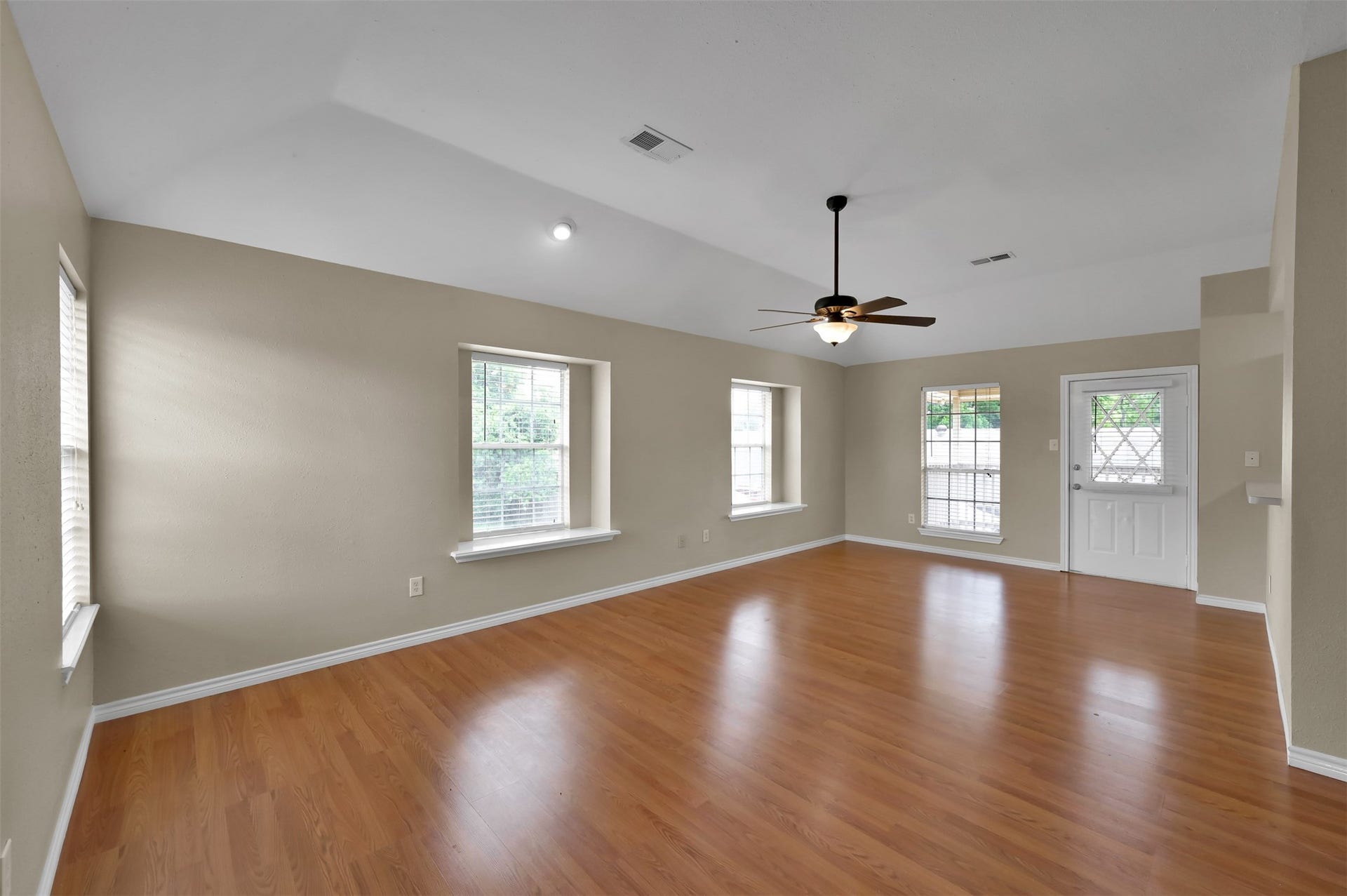 1141 Lovett Street, Tomball, TX 77375 Spacious living area with rich wood flooring, abundant natural light from multiple windows, and a stylish ceiling fan for comfort.