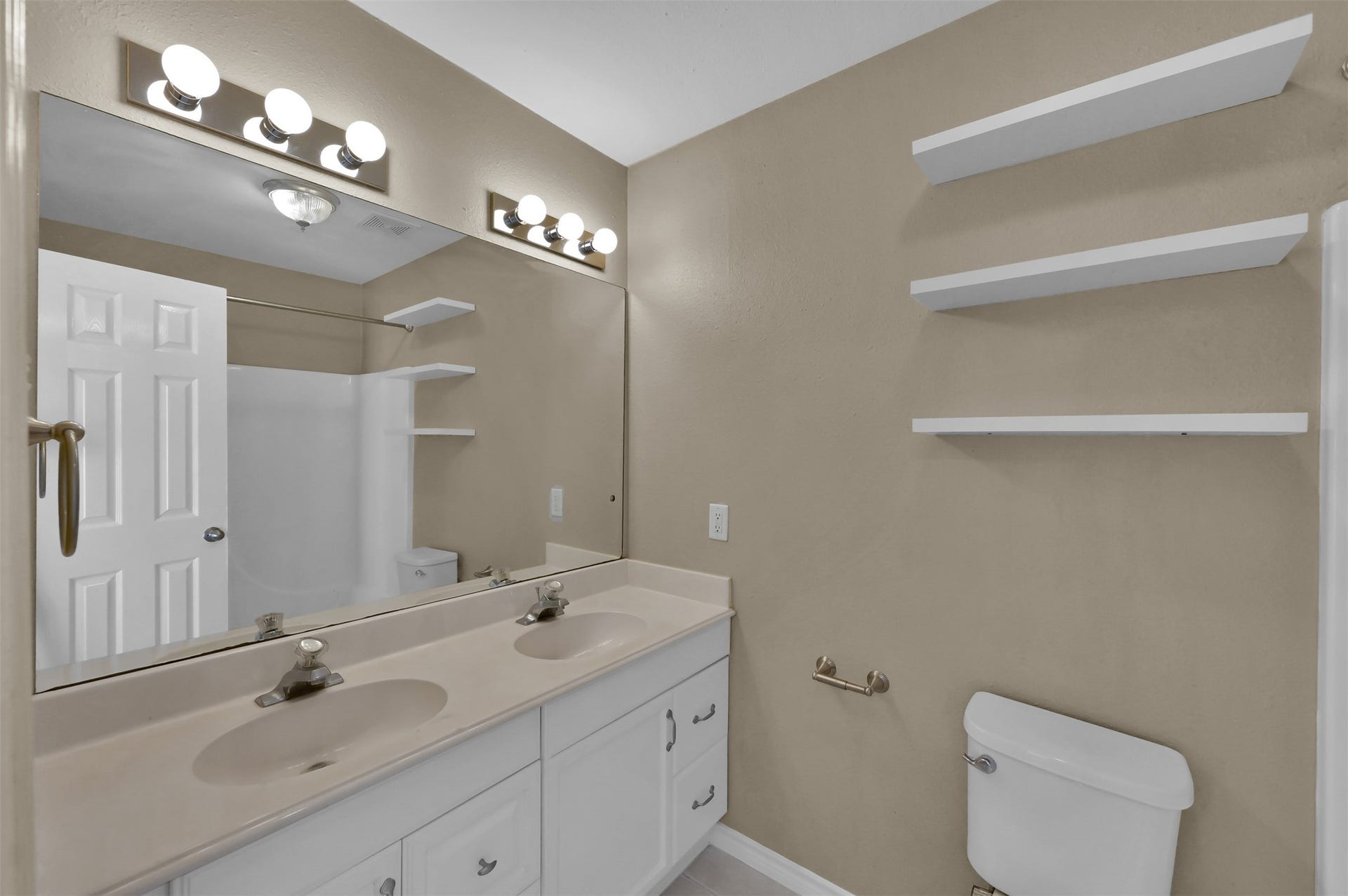 1141 Lovett Street, Tomball, TX 77375 Bathroom featuring a double vanity with ample lighting, sleek mirrors, and convenient open shelving for storage.