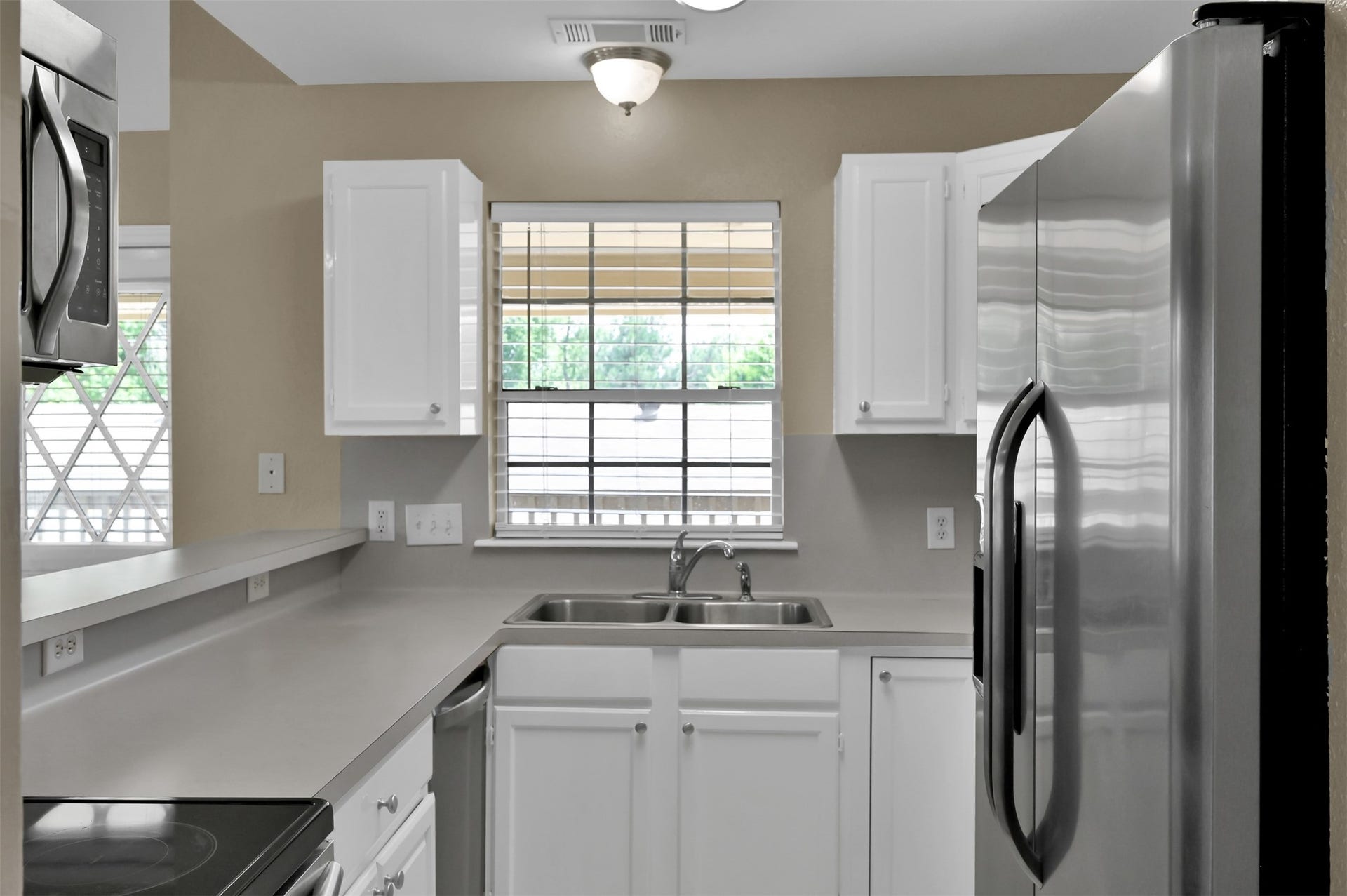 1141 Lovett Street, Tomball, TX 77375 Modern kitchen featuring sleek stainless steel appliances, white cabinetry, and a bright window for natural light.
