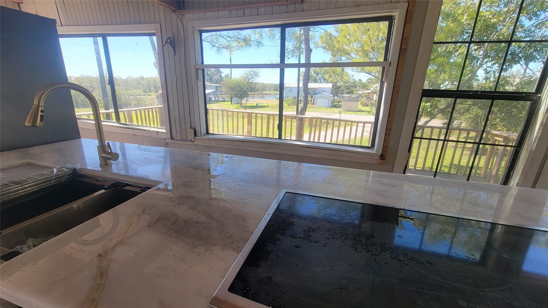12018 Sandpiper Road, Angleton, TX 77515 This photo showcases a kitchen with large windows offering a scenic view. The space features a modern countertop with an integrated sink and cooktop, creating a bright and inviting atmosphere.