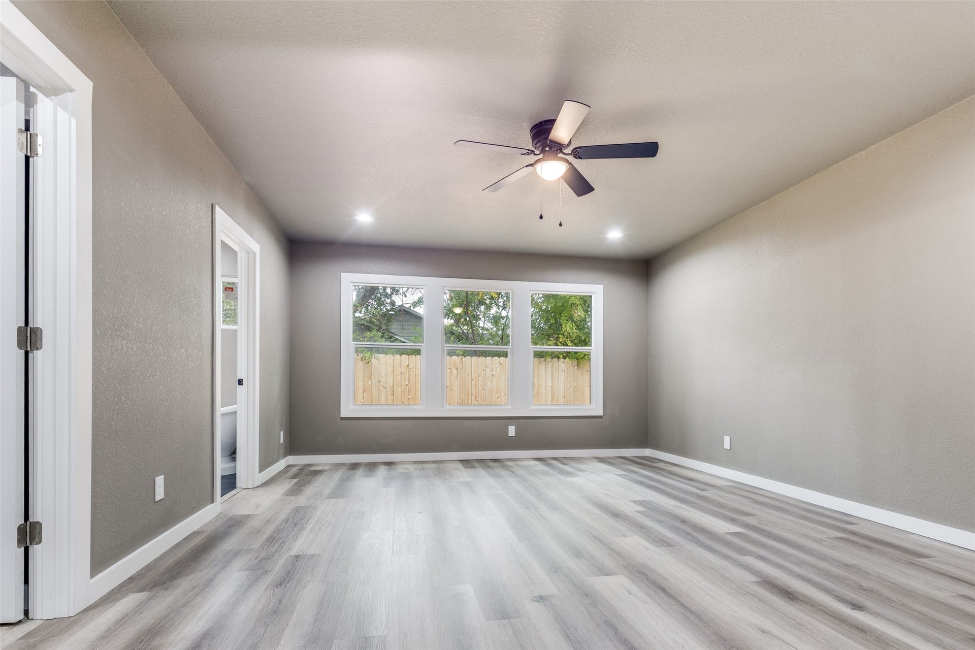 Spacious primary bedroom with new floors, ceiling fan, and great natural light, ideal for guests, a nursery, or a home office.