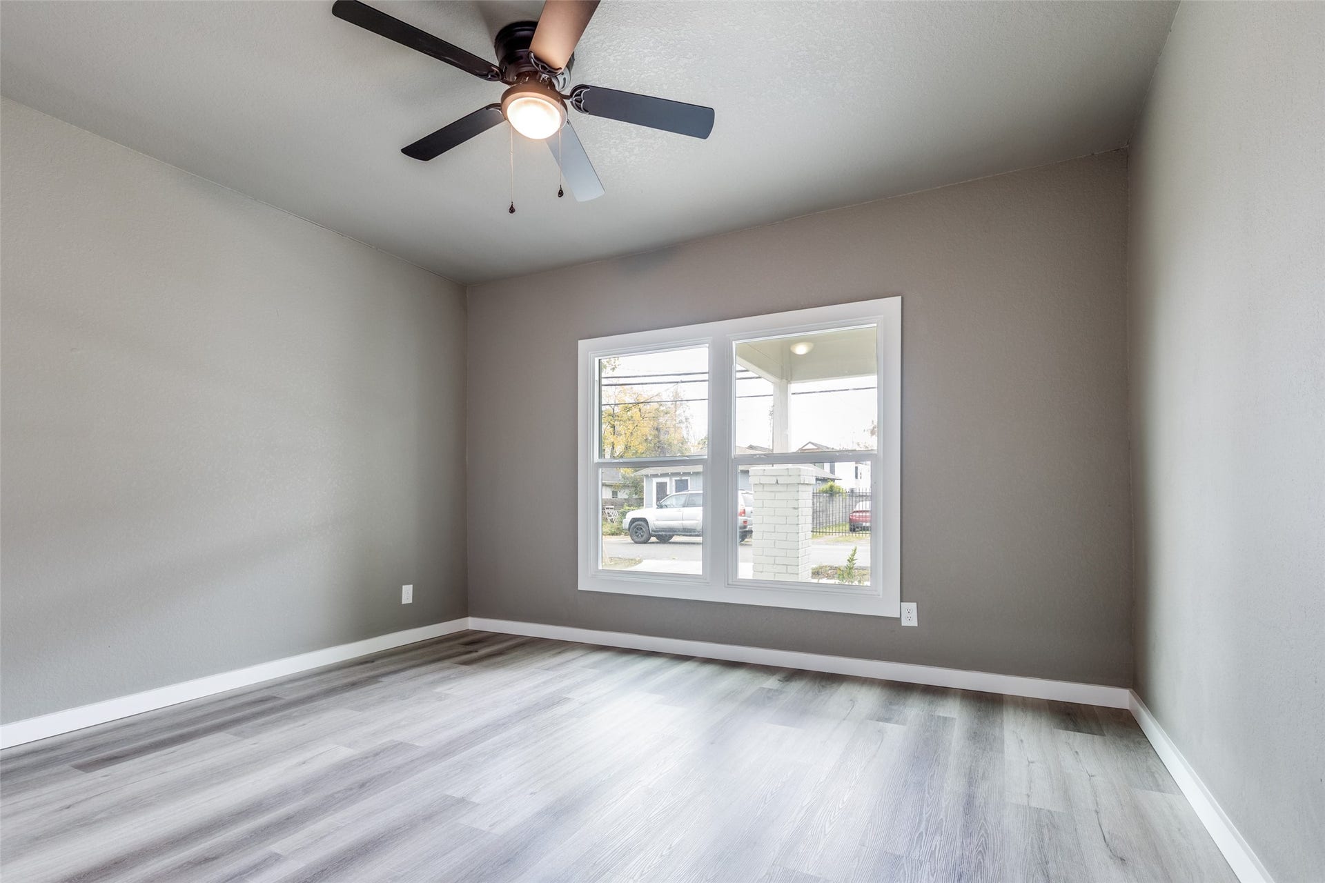 Sunny bedroom with new flooring, ceiling fan, and a calm neutral palette, perfect for a guest room, office, or flex space.