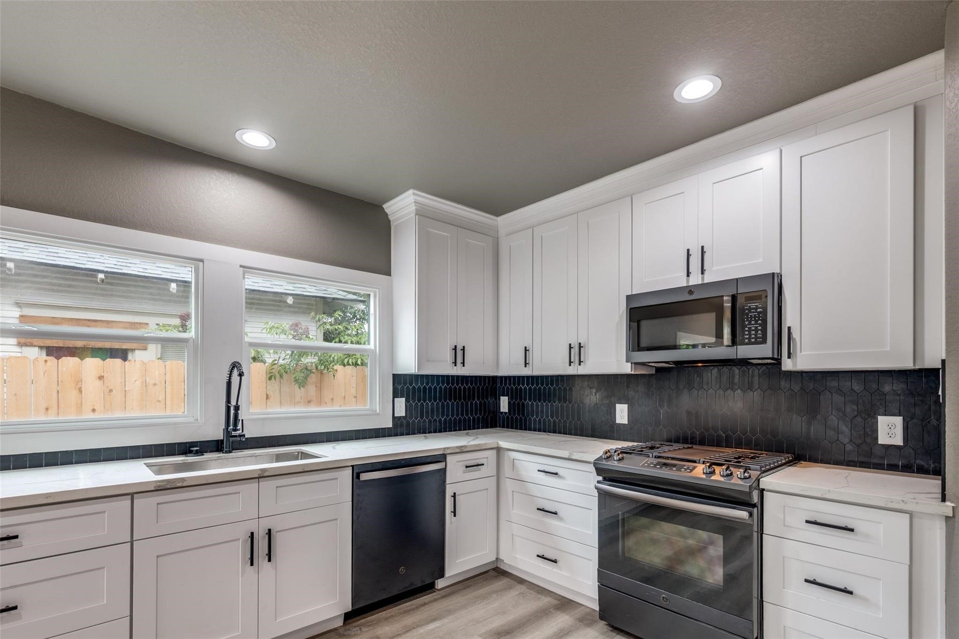 Classic white kitchen with real style and storage, featuring black stainless steel appliances and easy flow to the living space.