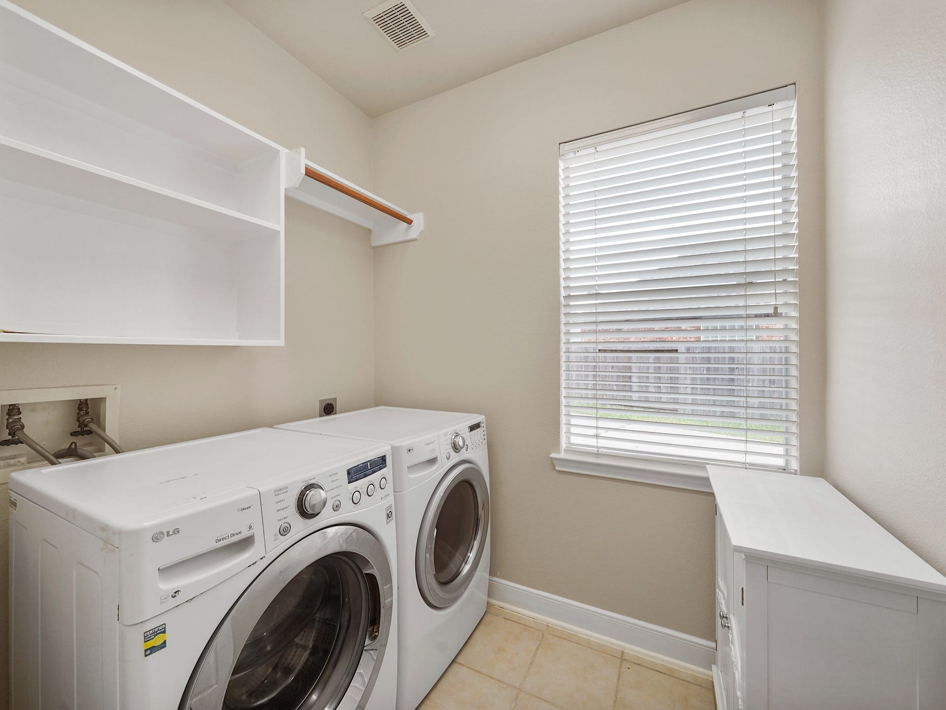 3907 Garnet Falls, Sugar Land, TX 77479 The laundry room has a washer and dryer with shelving for storage.