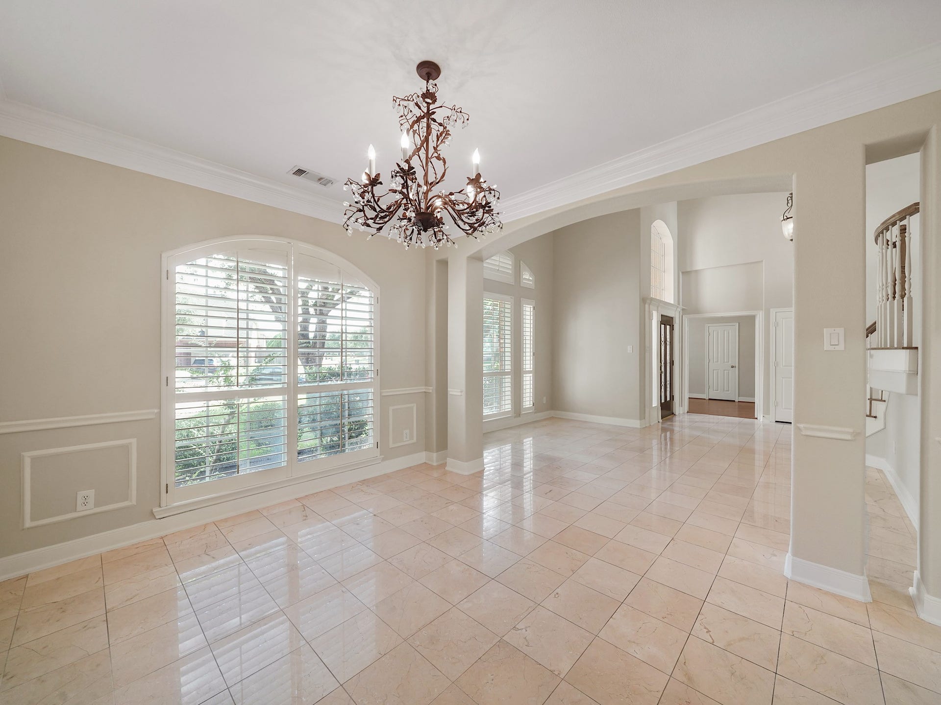 3907 Garnet Falls, Sugar Land, TX 77479 This dining area features large windows with plantation shutters, a chandelier, and tile floors. The space opens up to an inviting entryway with high ceilings.