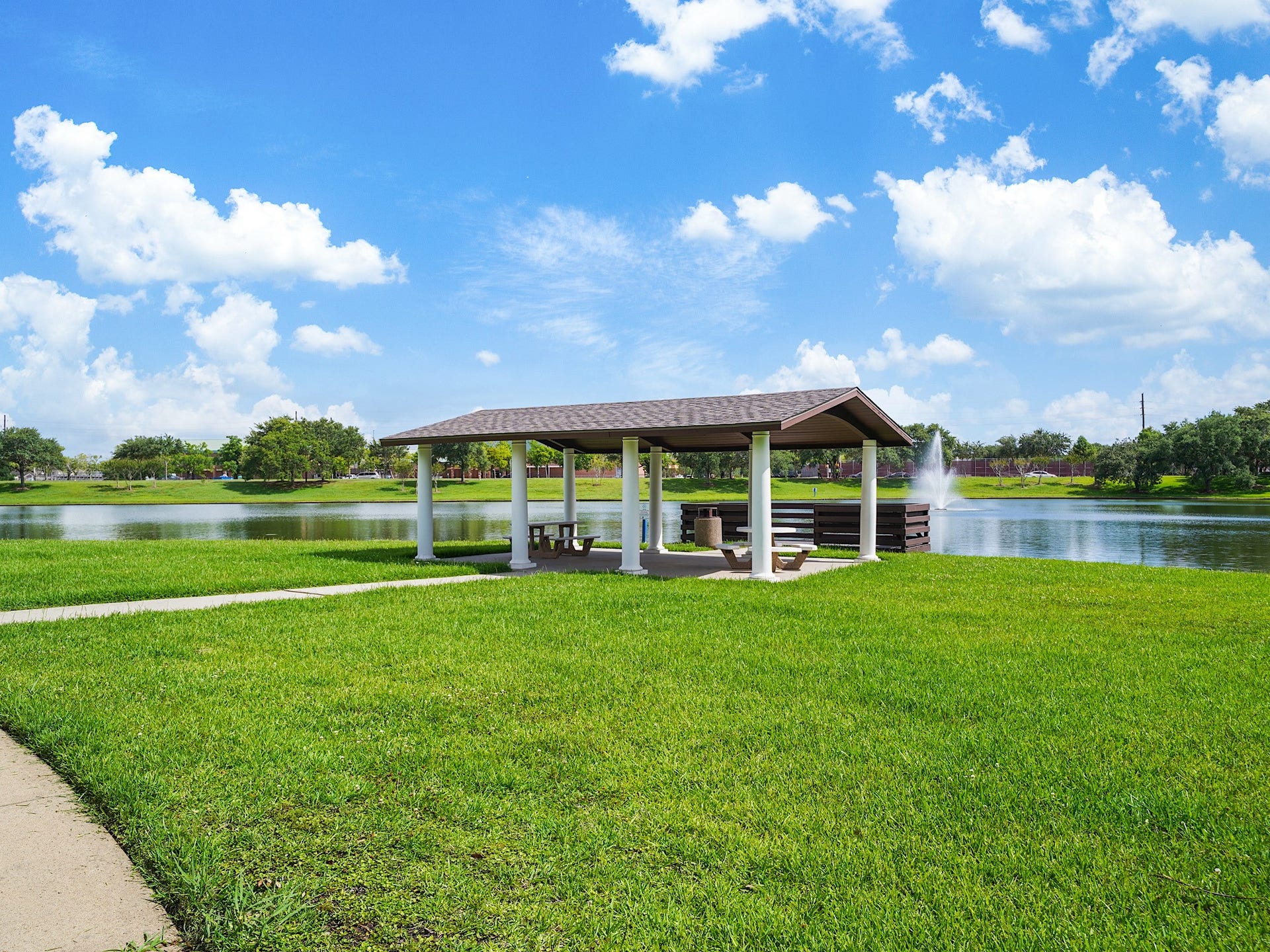 3907 Garnet Falls, Sugar Land, TX 77479 A pavilion area featuring picnic tables and a wooden deck overlooking the pond, ideal for relaxation and enjoying nature.