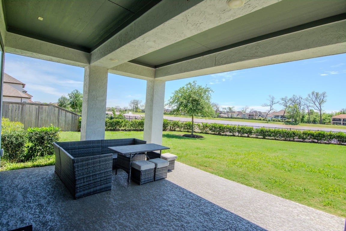 5423 Priamus Drive, Missouri City, TX 77459 This photo showcases a spacious covered patio with outdoor seating, overlooking a well-maintained lawn and a scenic view of the neighborhood, perfect for relaxation and entertaining.
