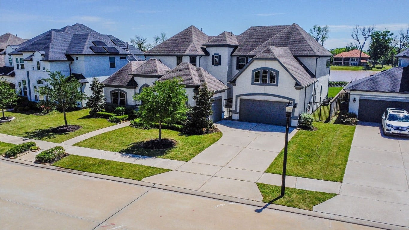 5423 Priamus Drive, Missouri City, TX 77459 This photo showcases a spacious, modern two-story home with a well-maintained front yard and driveway. The house features a multi-car garage and attractive landscaping, situated in a suburban neighborhood with nearby homes.