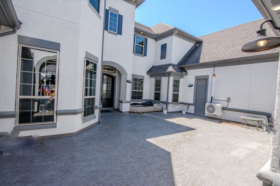 5423 Priamus Drive, Missouri City, TX 77459 This photo shows a spacious and bright courtyard area of a modern home, featuring large windows, a textured concrete floor, and elegant architectural details.