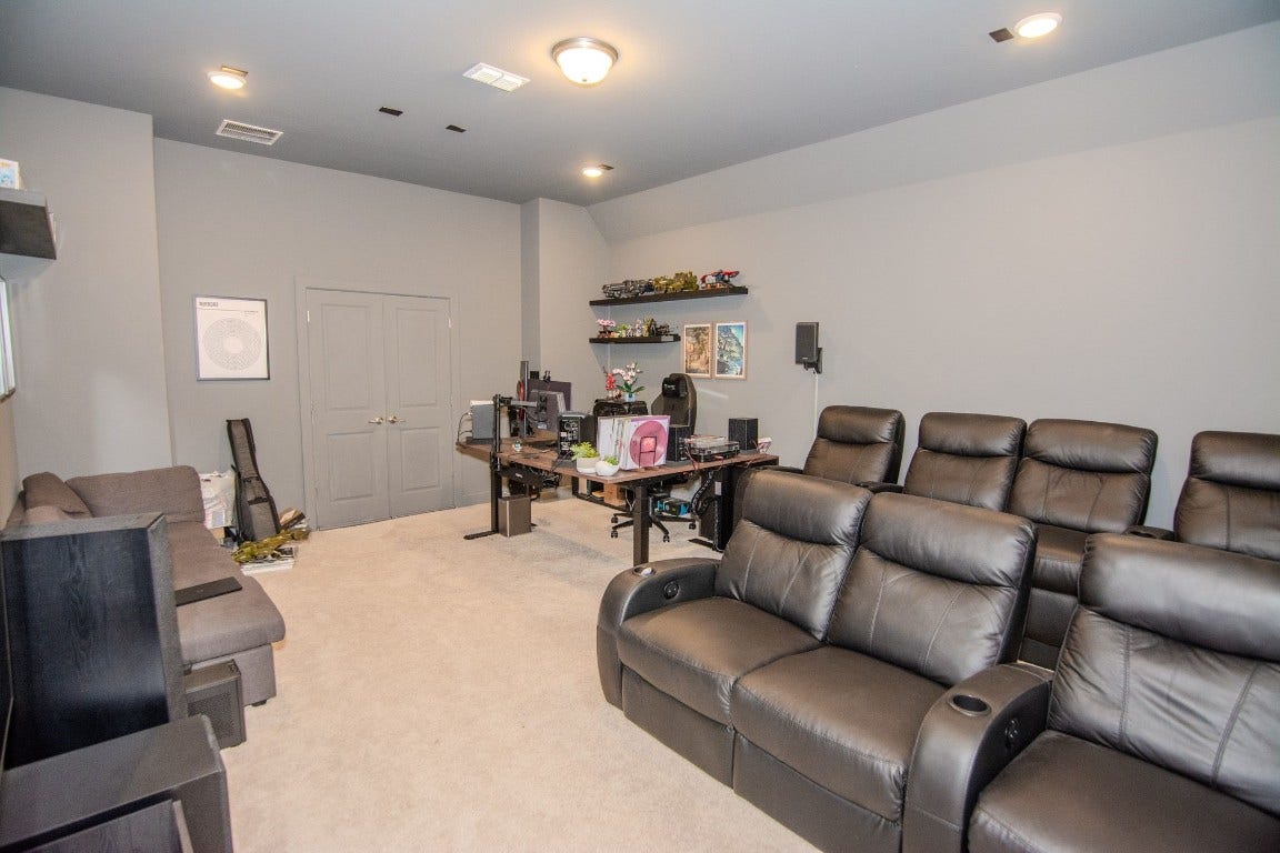 5423 Priamus Drive, Missouri City, TX 77459 This room features a cozy setup perfect for entertainment and work, with plush leather recliners and a desk area. The neutral-colored walls and carpet create a warm ambiance, while built-in shelving offers storage and display space. Ideal for a home theater and office combination.