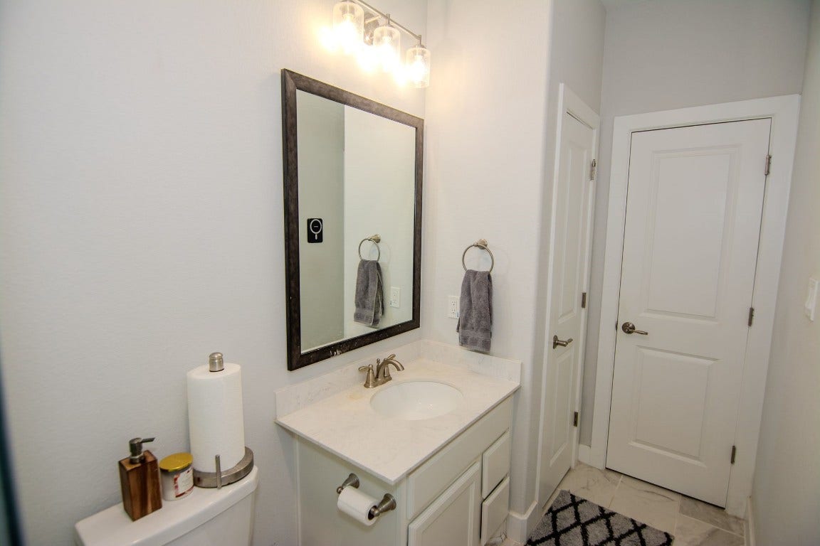 5423 Priamus Drive, Missouri City, TX 77459 This bathroom features a sleek design with a white vanity, all set against light walls and floor tiles, creating a clean and bright space.
