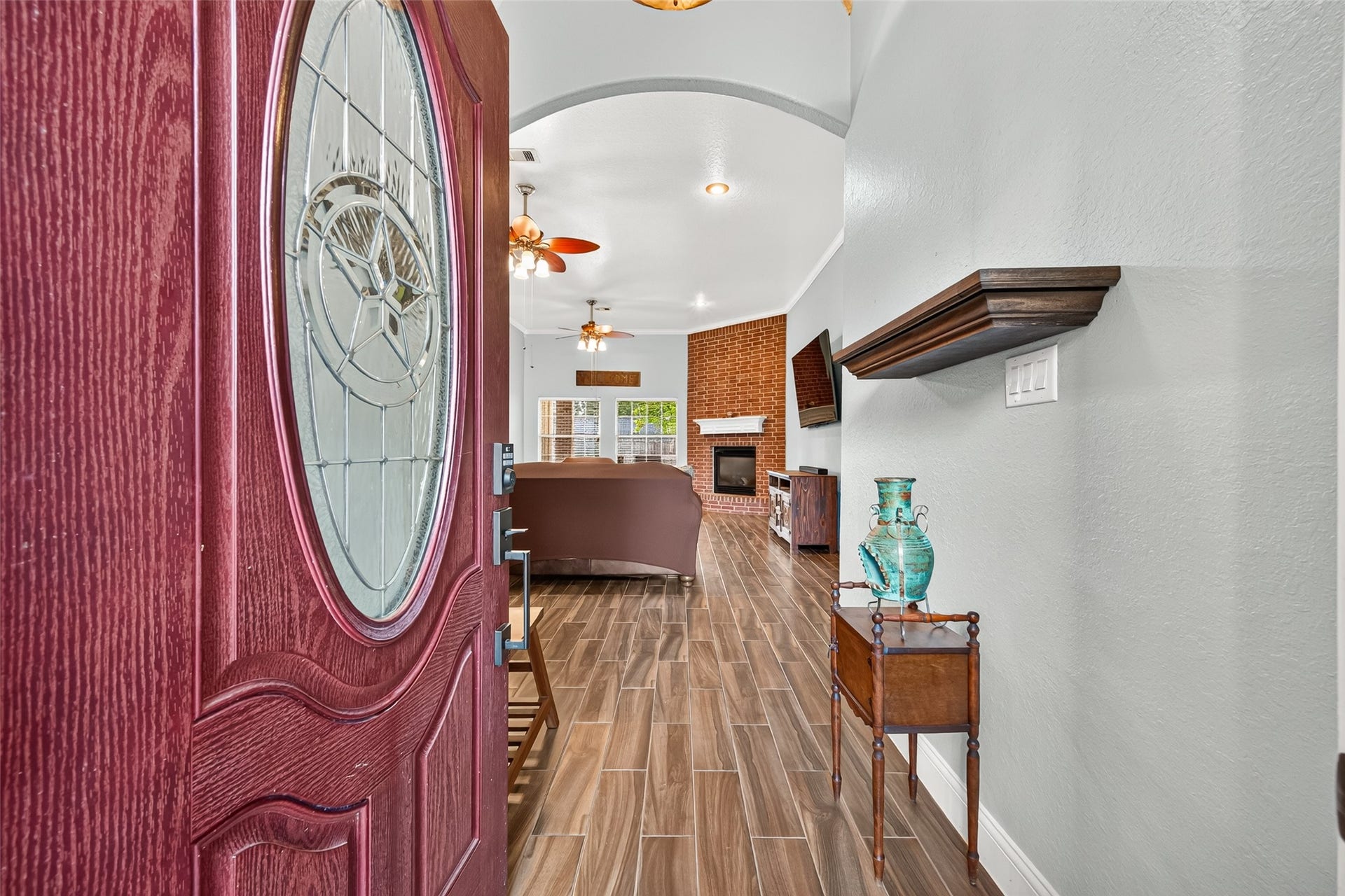 A warm welcome awaits! Beautiful entryway featuring a decorative front door, rich wood-look flooring, and an inviting view into the home.
