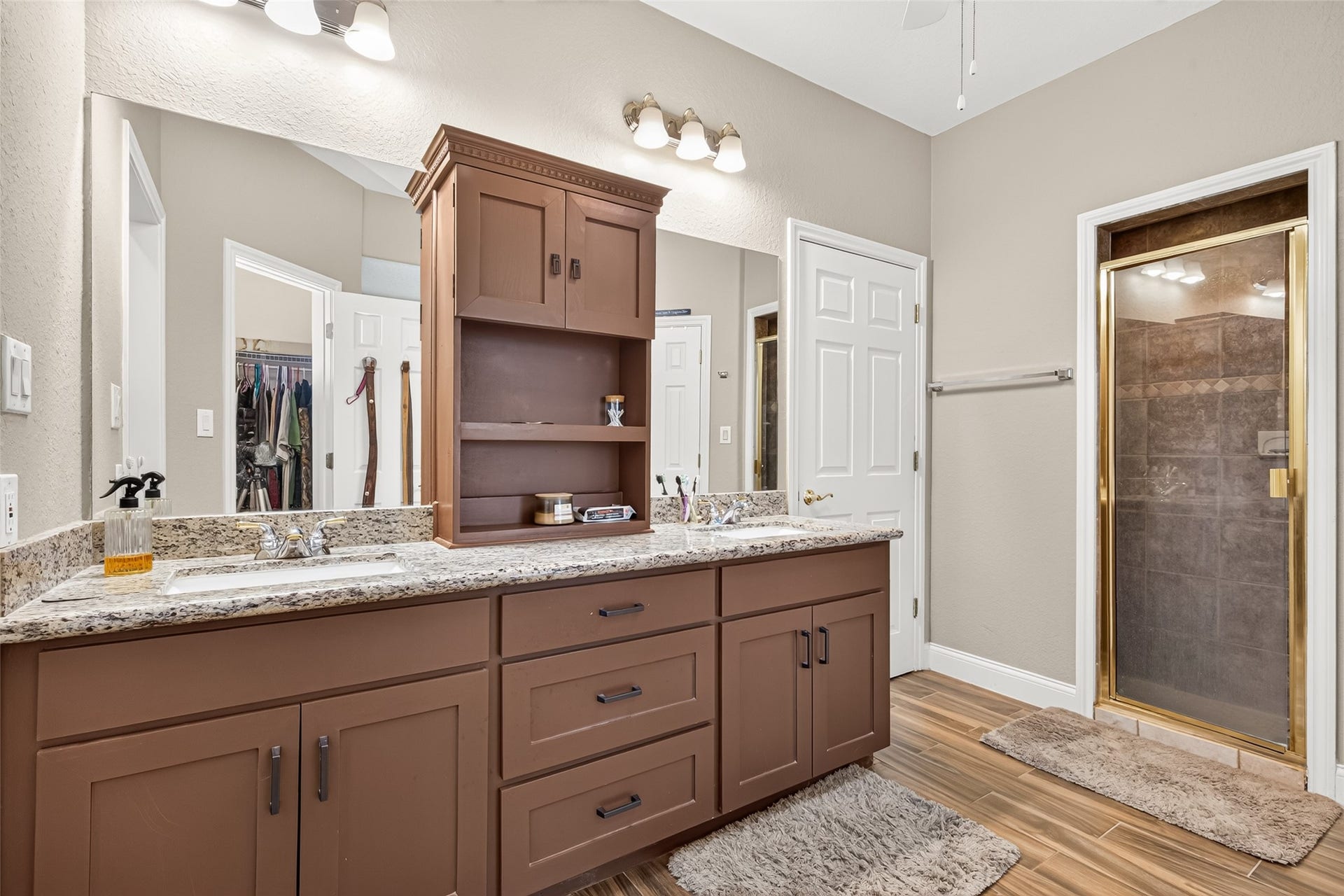 Beautiful custom vanity featuring rich cabinetry, double sinks, generous counter space, and decorative lighting.
