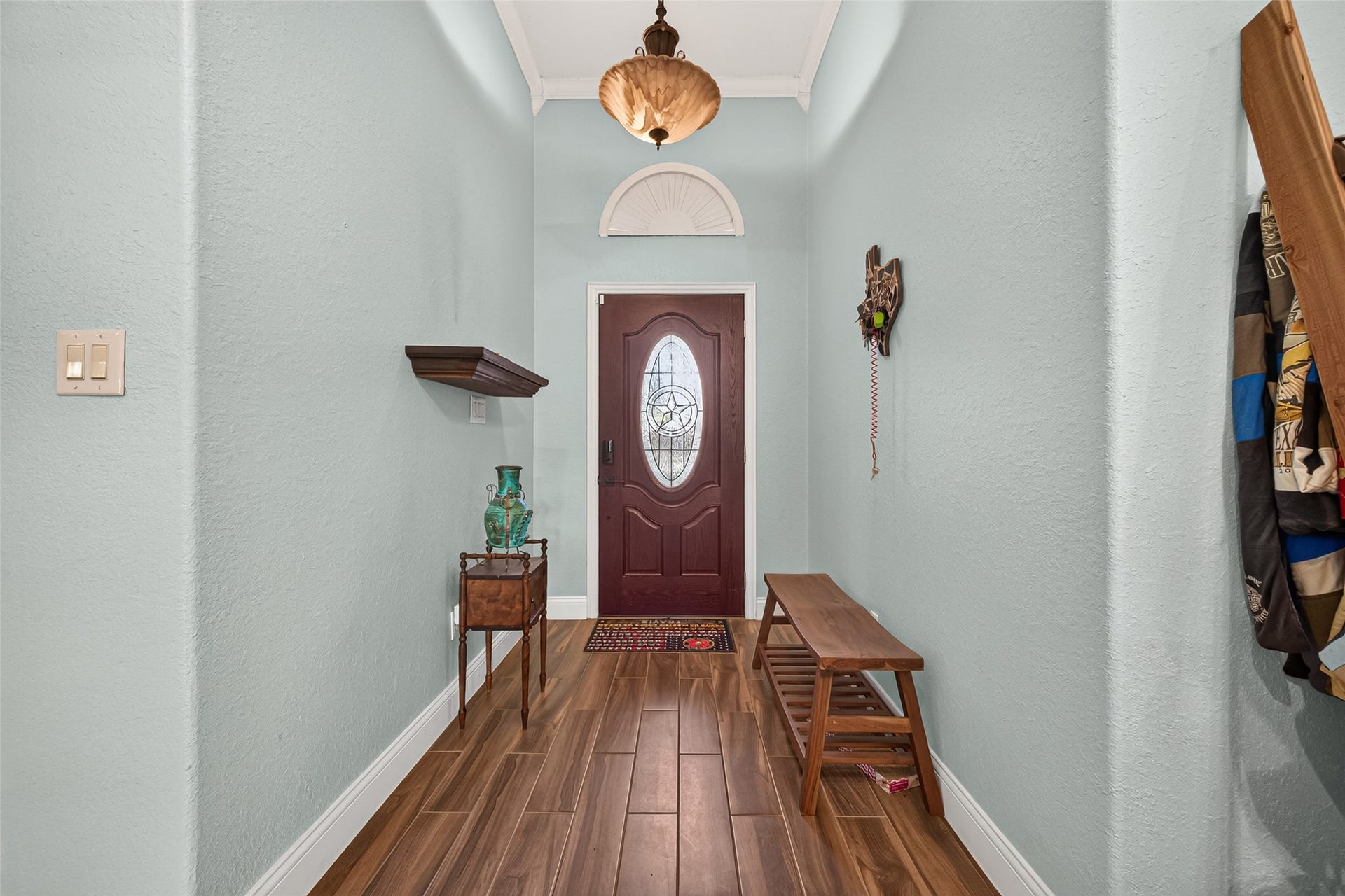 Step inside to a spacious entry hall featuring beautiful flooring, soft blue walls, and decorative lighting that creates a welcoming first impression.