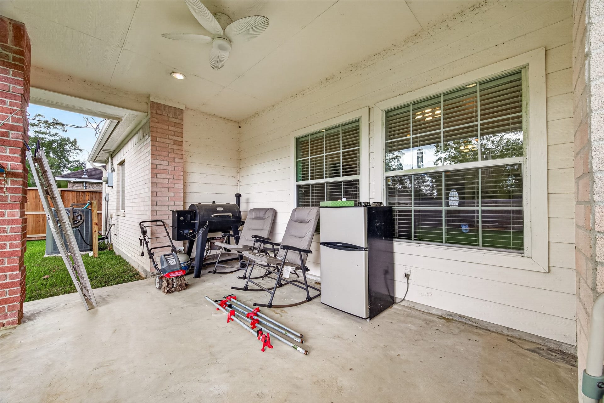 Enjoy outdoor living on this spacious covered patio featuring ceiling fans, brick accents, and plenty of room for comfortable seating.