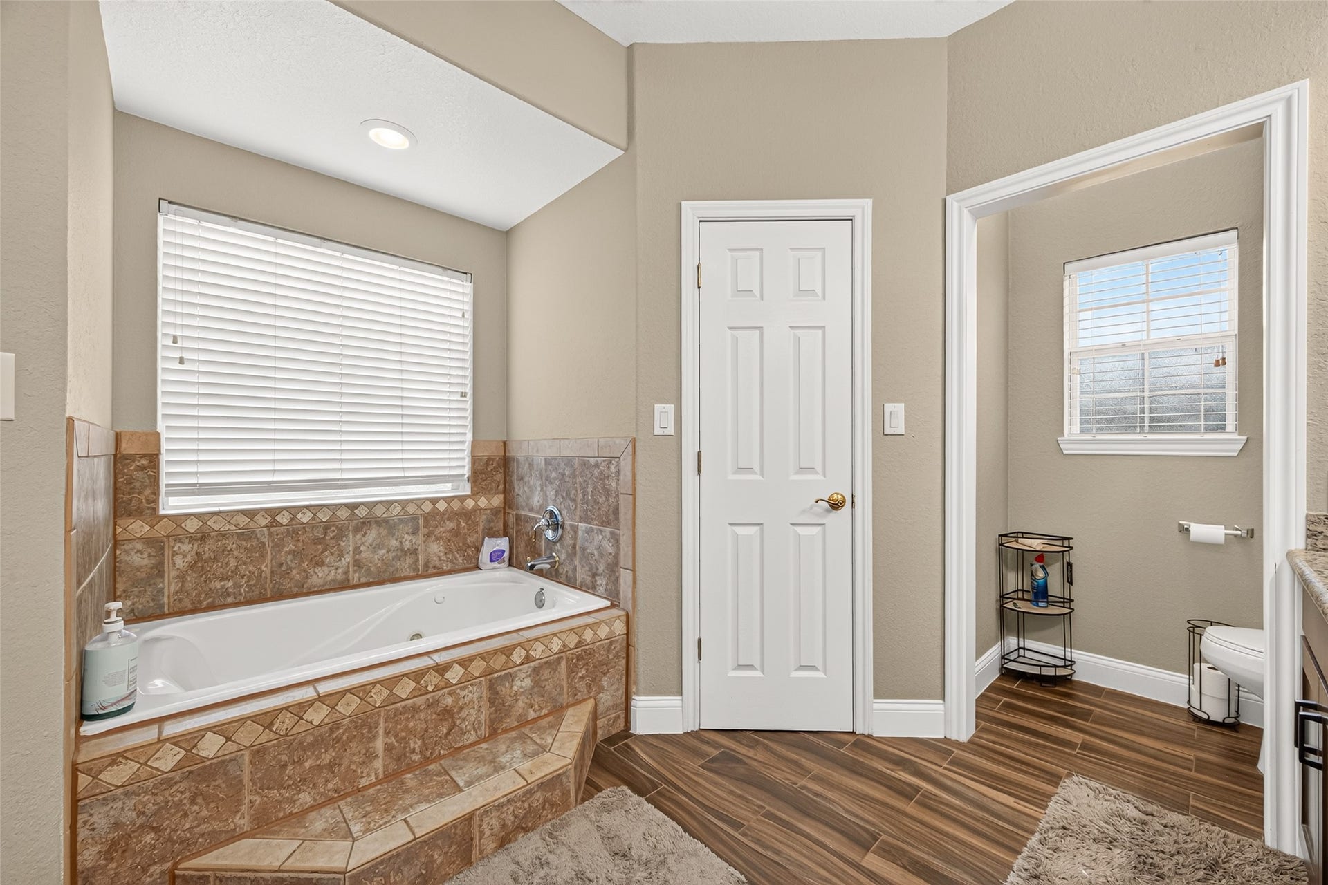 Unwind after a long day in the inviting soaking tub, surrounded by windows that bring natural light into the primary bathroom.