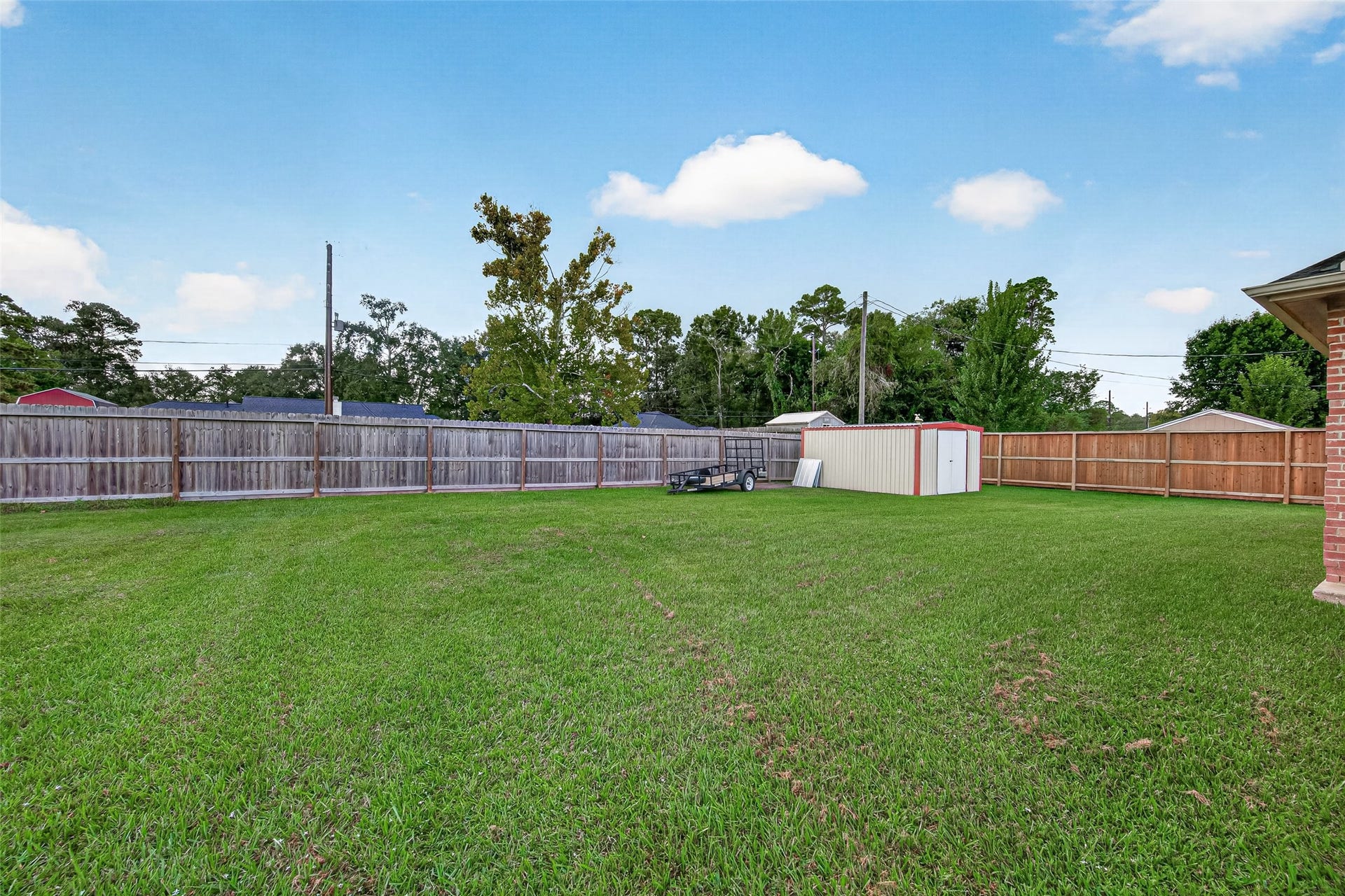 Another view of the spacious backyard featuring a privacy fence, mature trees, and plenty of room to create your own outdoor retreat.