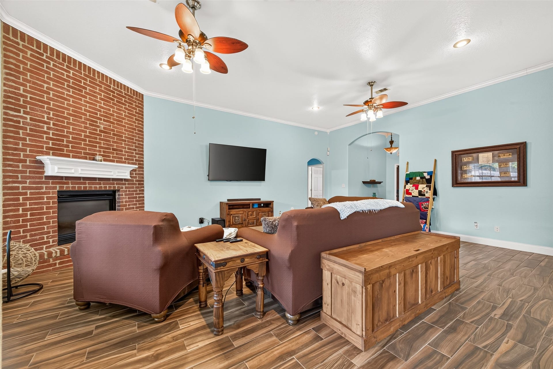 The beautiful brick fireplace creates a stunning focal point in this generously sized living room, complete with ceiling fans and warm, inviting finishes.