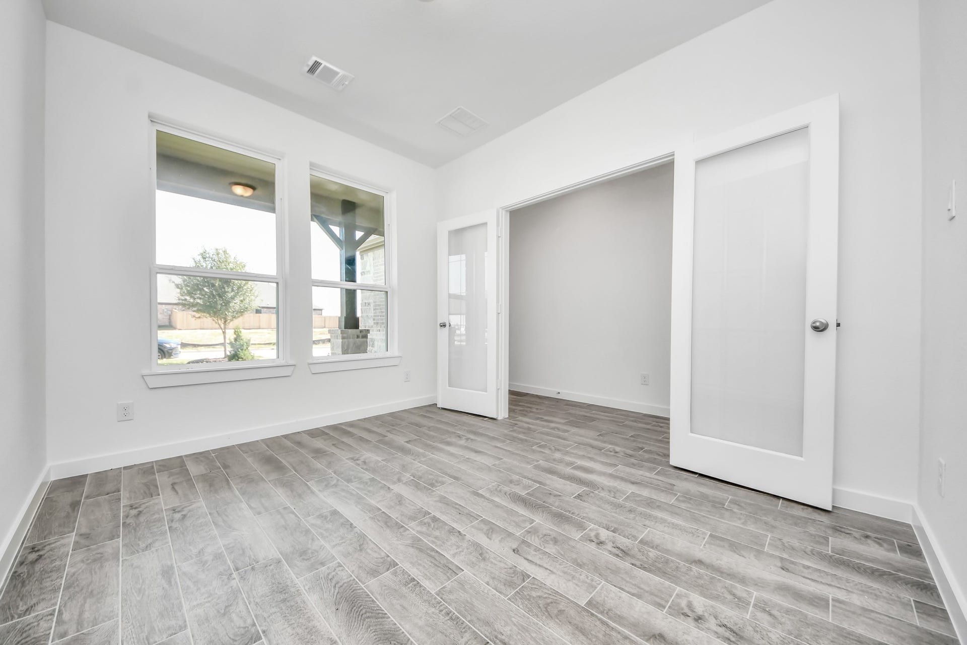 3057 Spoolwood Trail, Magnolia, TX 77355 Experience the perfect blend of sophistication and warmth in this home office, boasting elegant wood-look tile flooring and flooded with natural light from expansive windows and French doors.