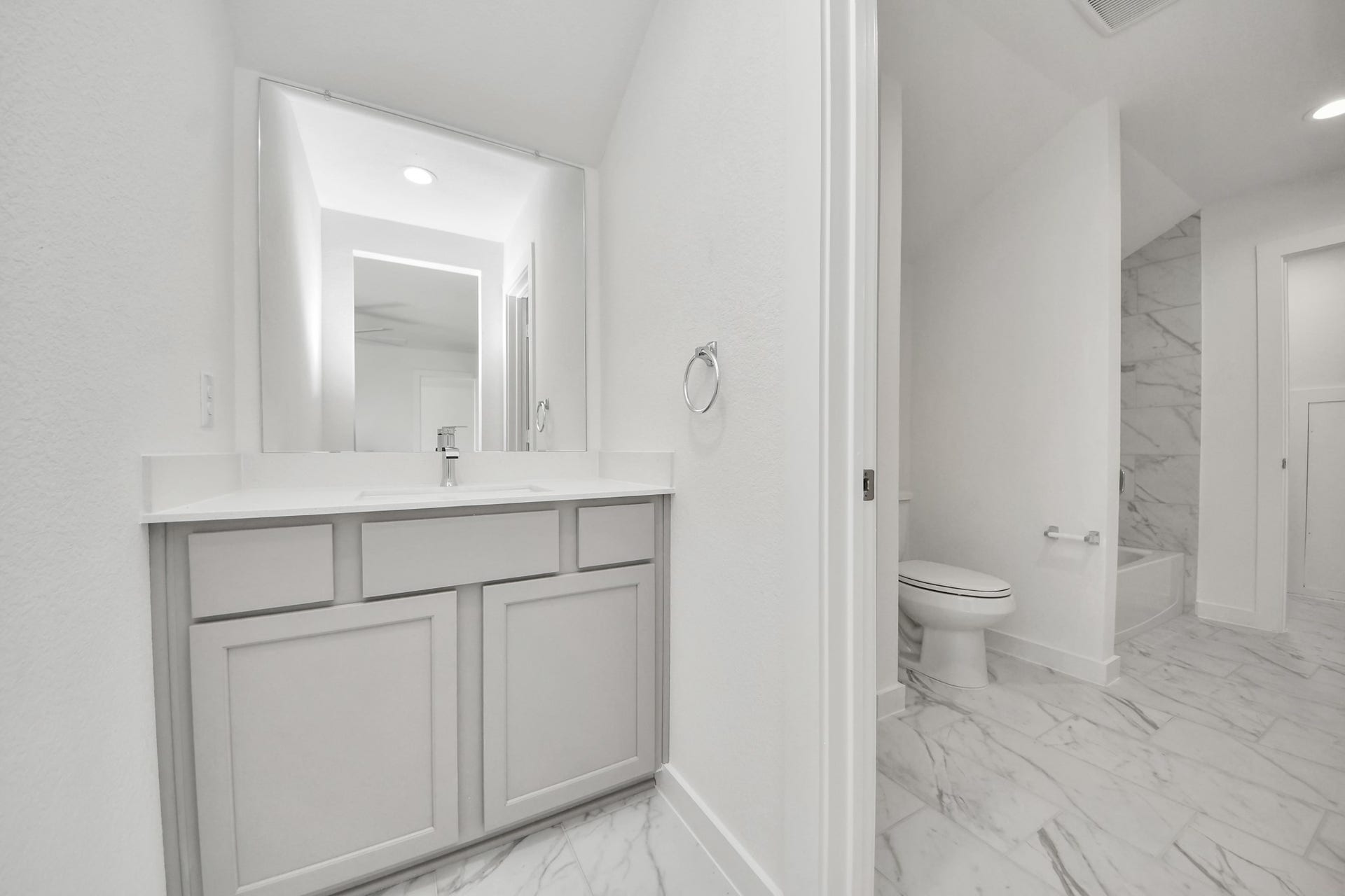 3057 Spoolwood Trail, Magnolia, TX 77355 Experience convenience in the secondary bathroom, designed for Jack and Jill arrangements, now with a separate vanity area. This well-appointed space showcases stylish tile flooring, a bath/shower combo with an elegant tile surround, and light-stained wood cabinets. The beautiful light countertop adds a touch of sophistication, combining functionality and aesthetics seamlessly.
