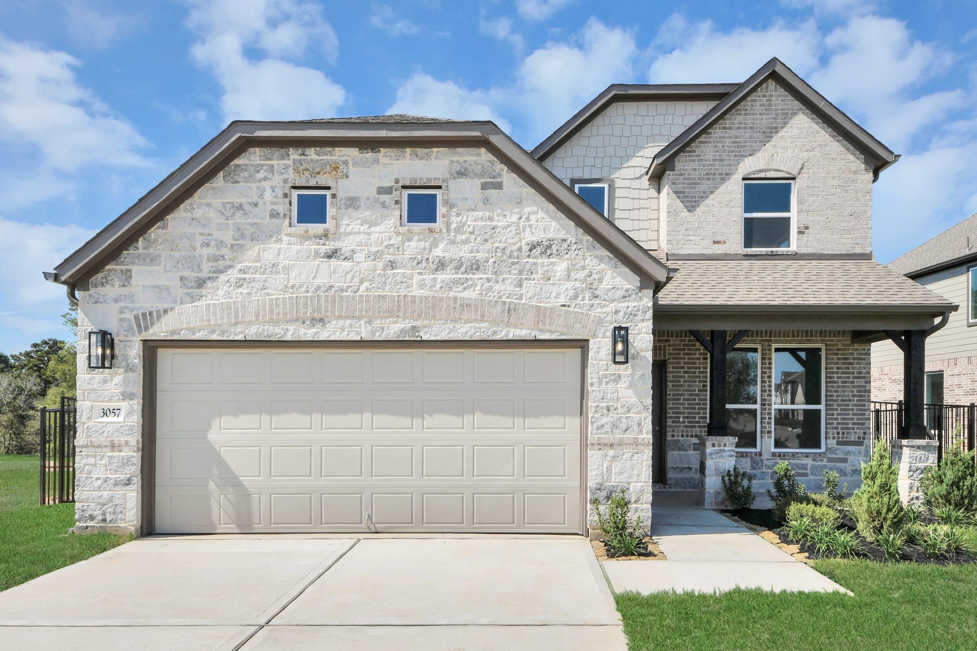 3057 Spoolwood Trail, Magnolia, TX 77355 Meticulously maintained yard and lush landscape, paired with a premium elevation featuring captivating brick accents. Modern coach lights add a touch of contemporary elegance to the exterior.